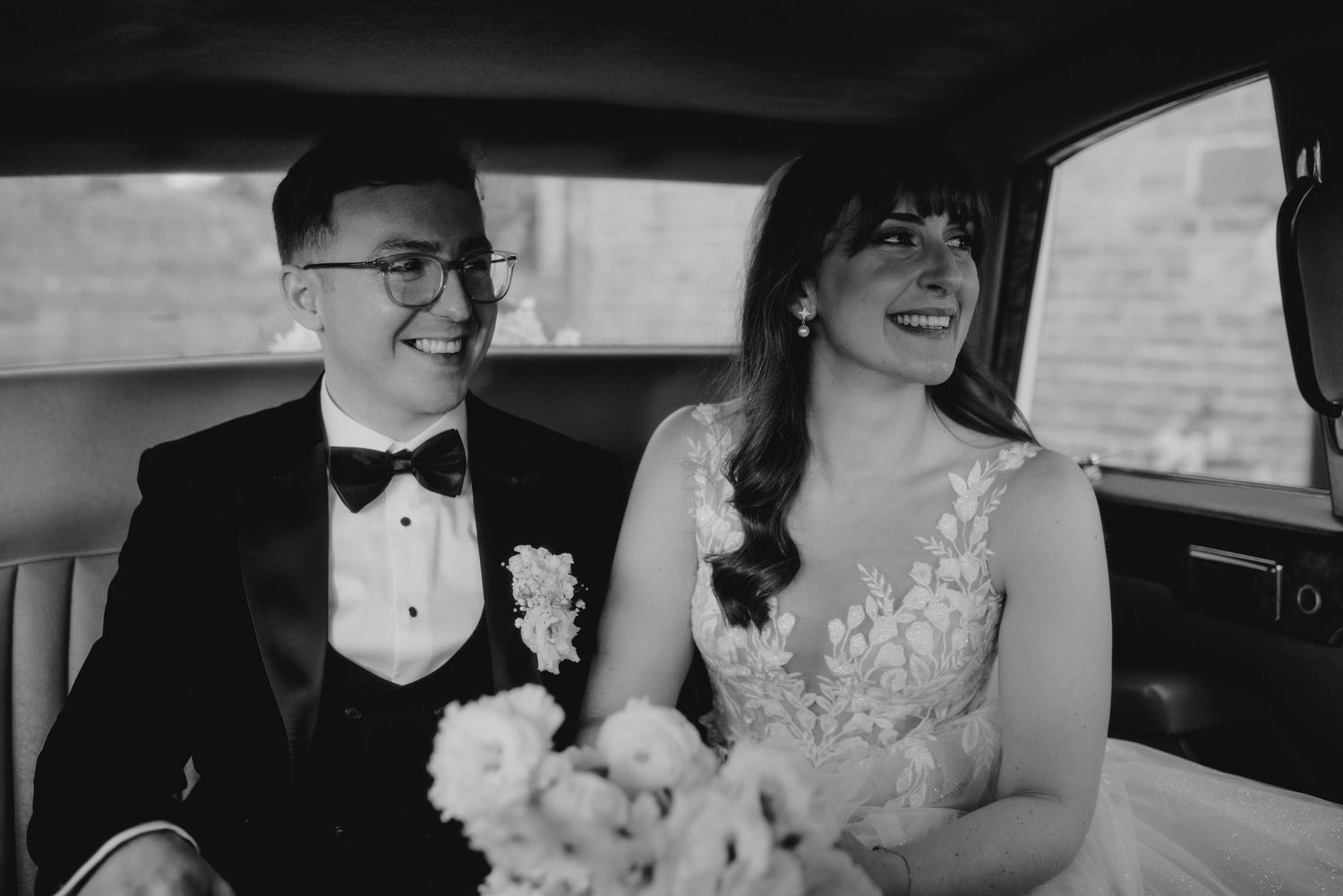 Wedding couple shares a joyful moment inside a luxury car.