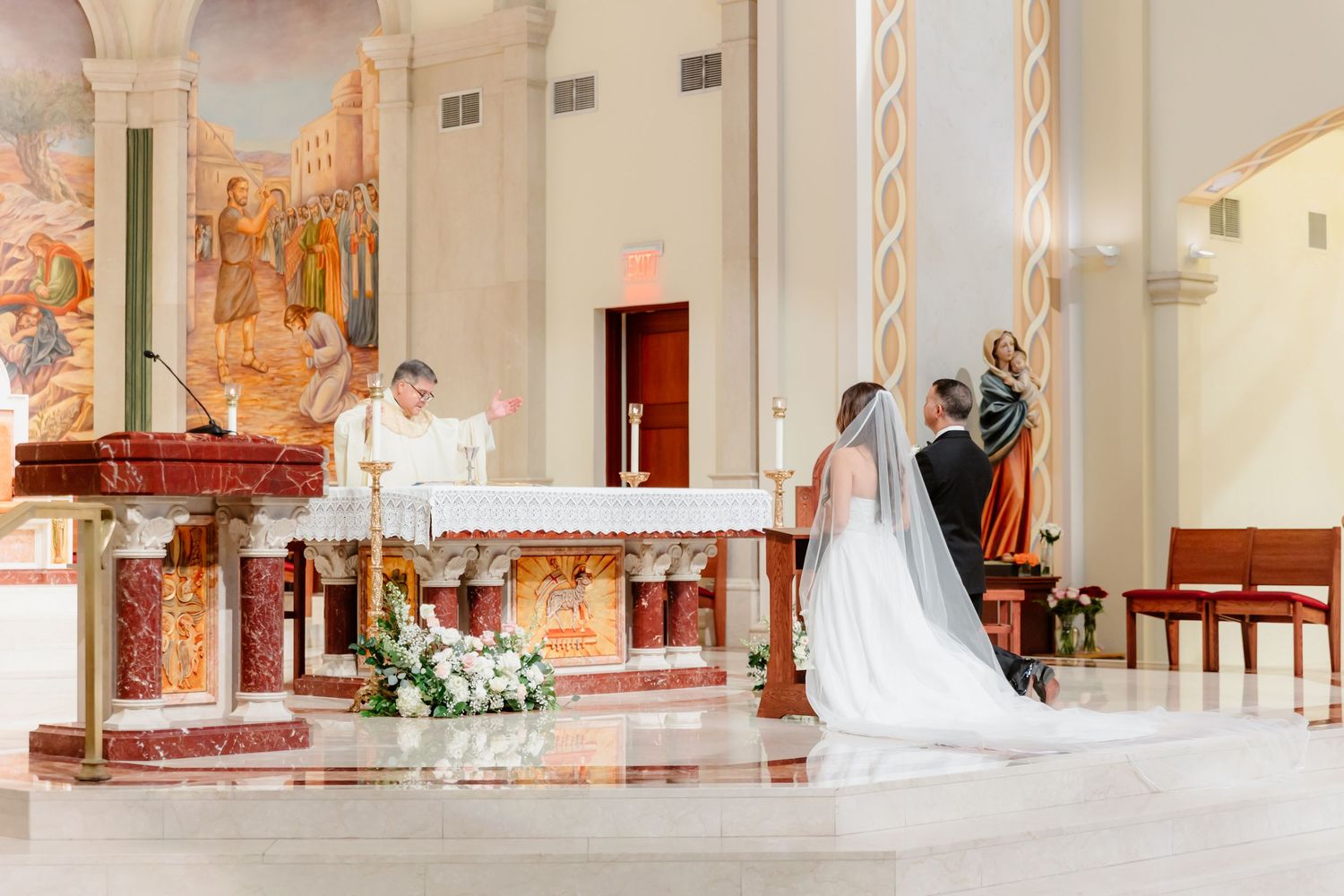 A panoramic view of a church interior during a wedding ceremony with white floral decorations and elegant architecture.