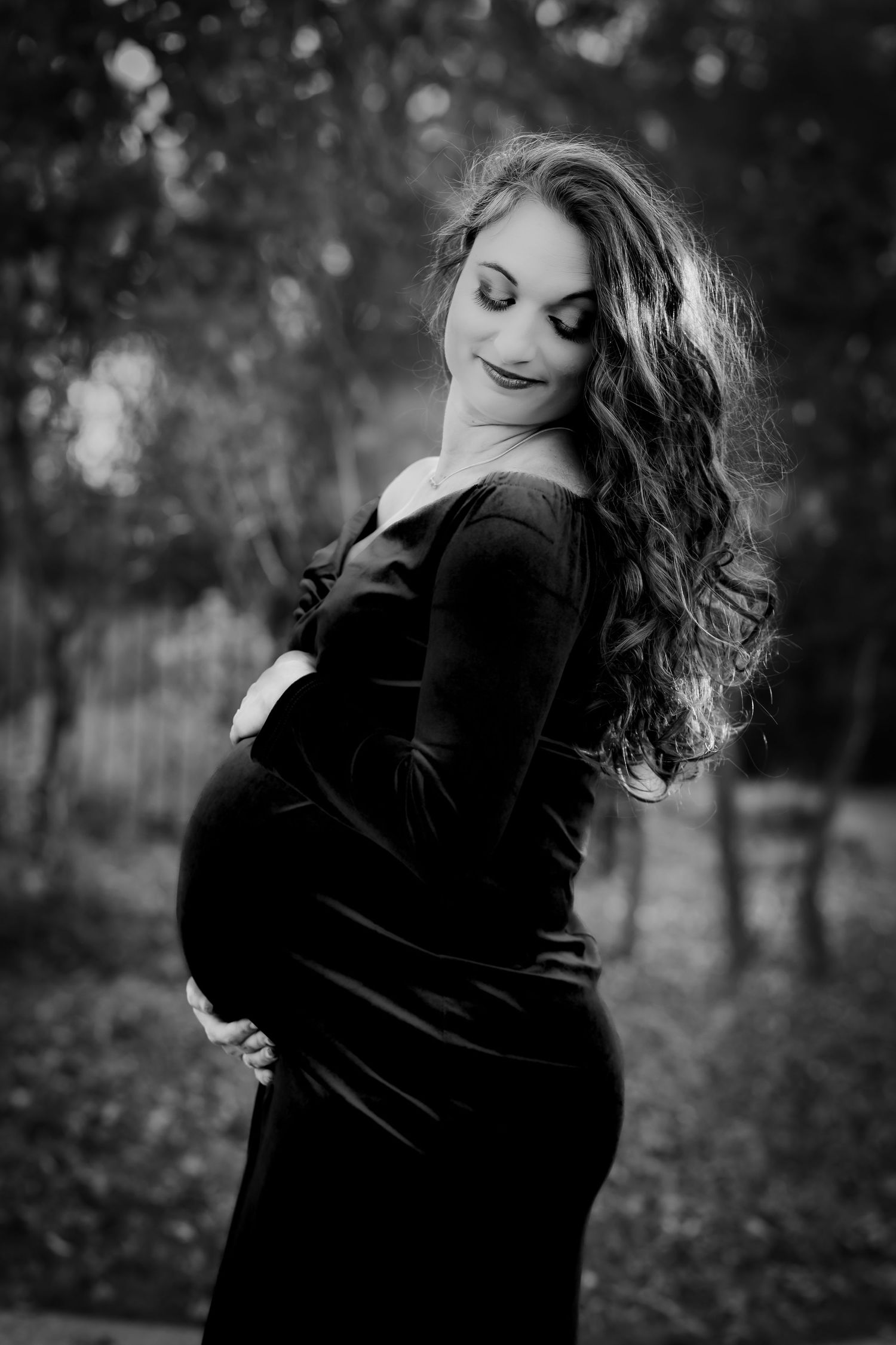 Stunning maternity picture featuring a long gown, beautiful colors, and a serene outdoor backdrop