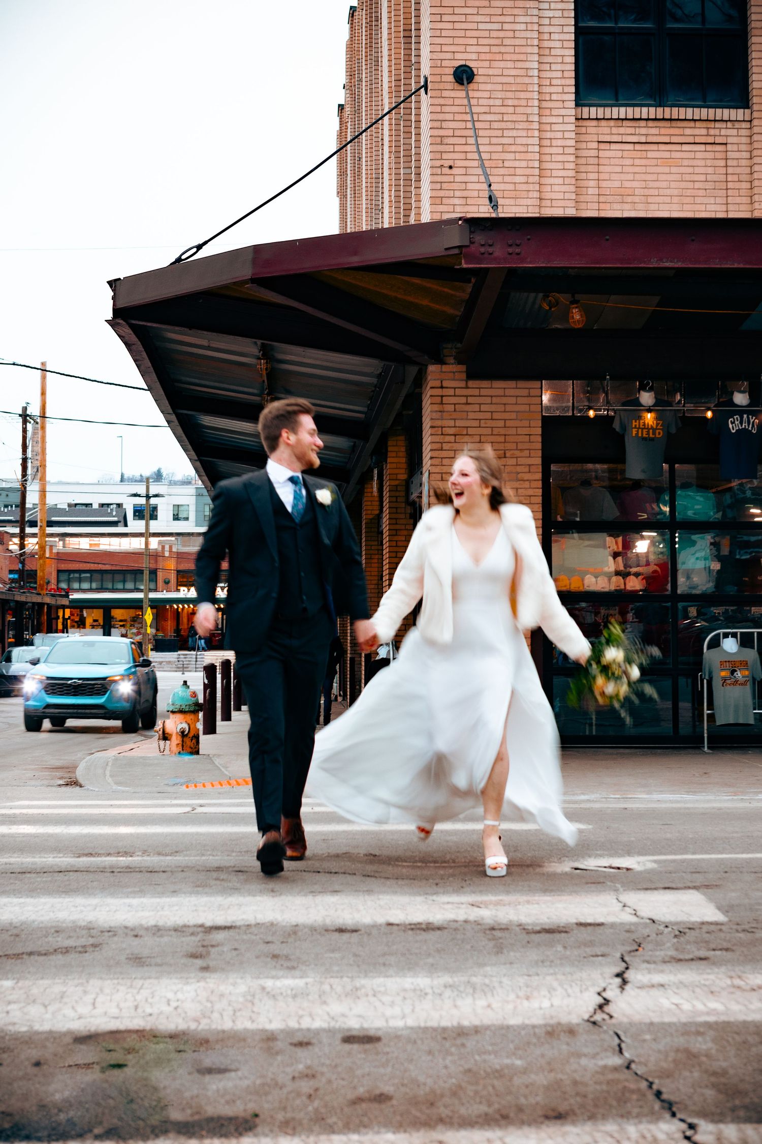 Bride and groom running across a street in natural light with soft, romantic colors.