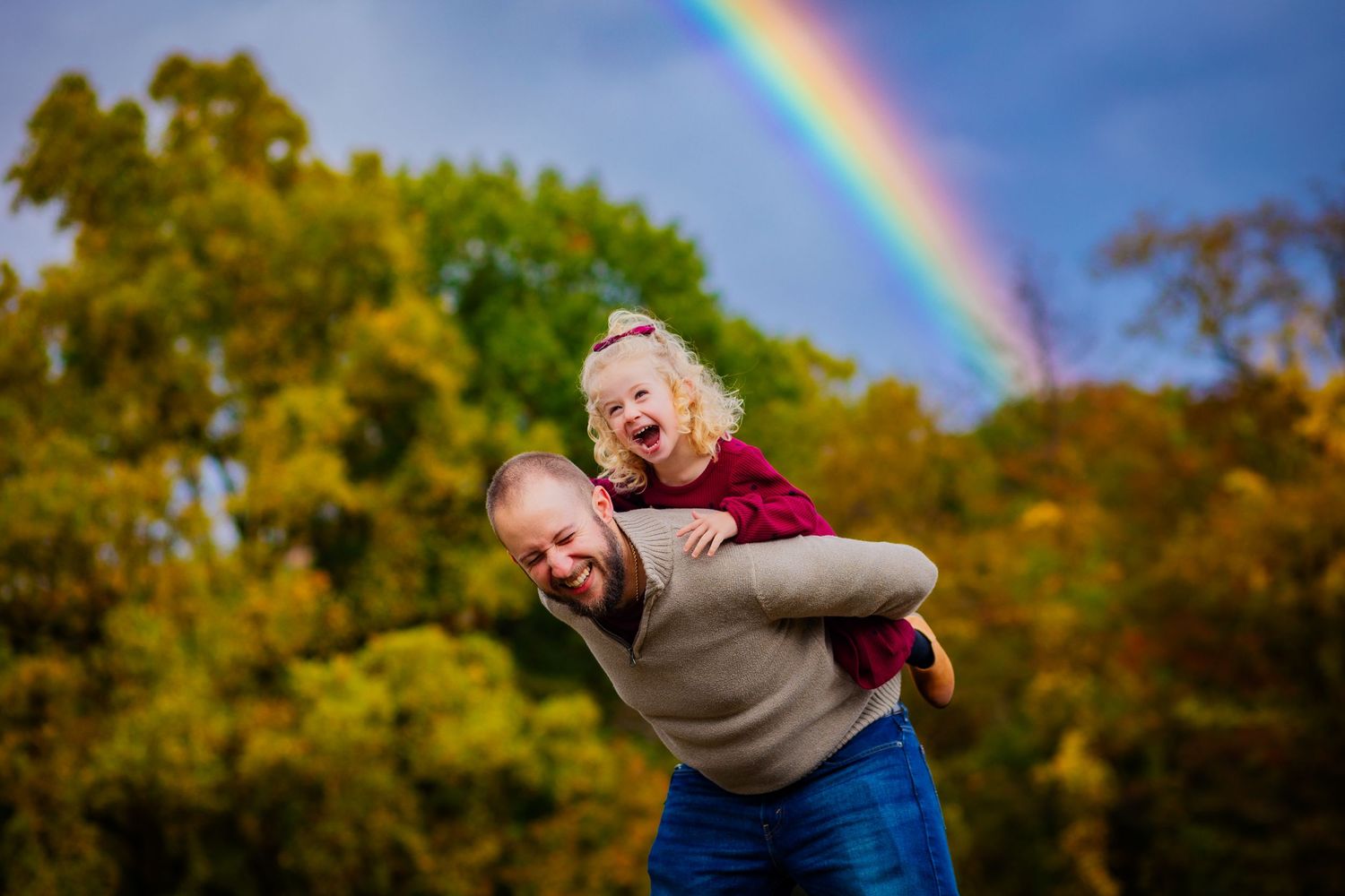 A fun, candid moment with a father and daughter playing under the beautiful rainbow