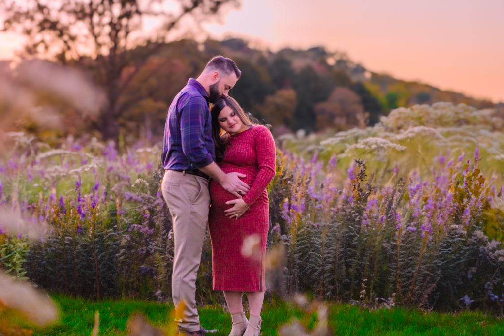 Pregnant woman posing with partner during a maternity session with warm, picture-perfect tones