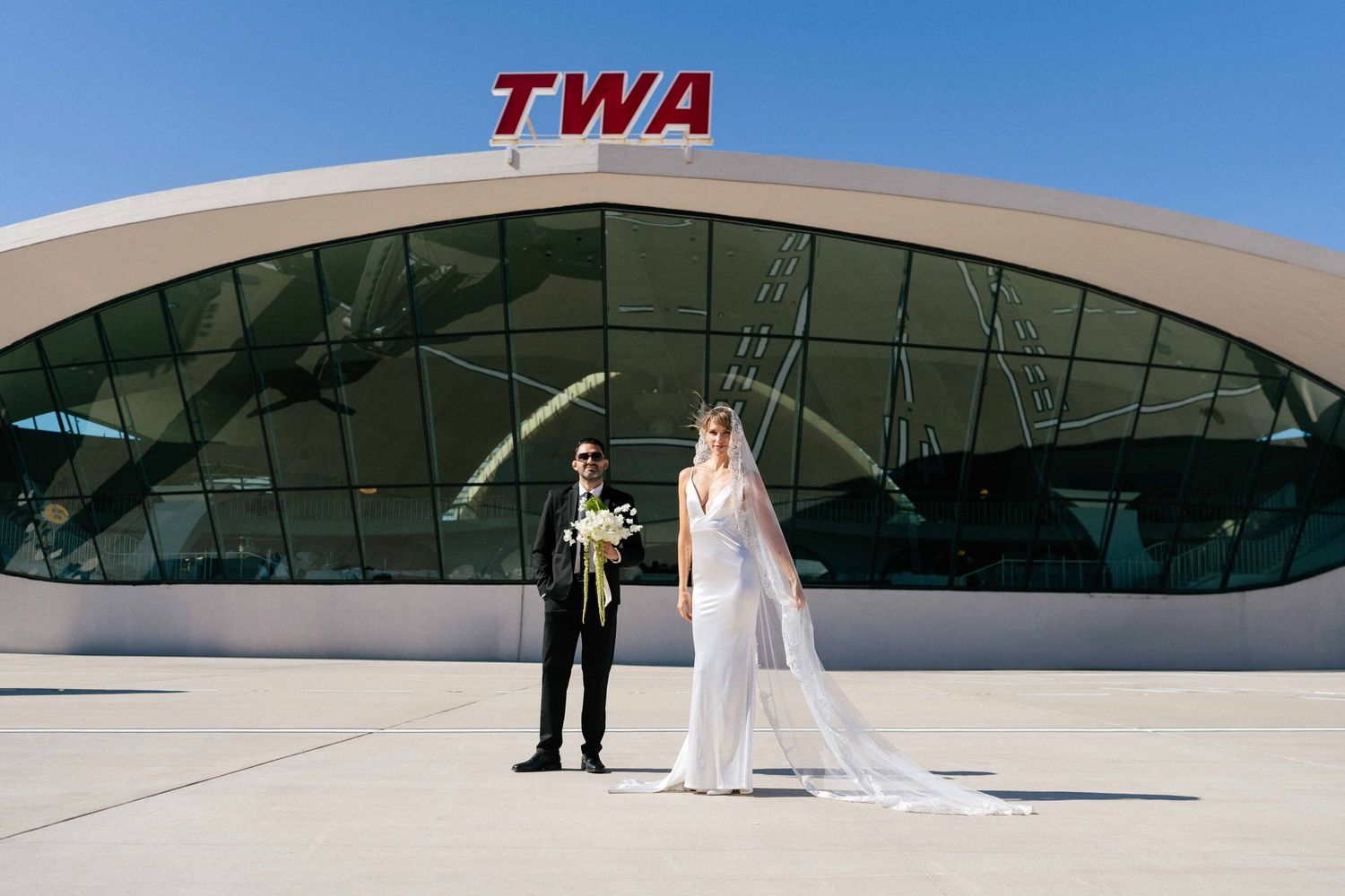 Wedding couple posing in front of iconic TWA terminal building.
