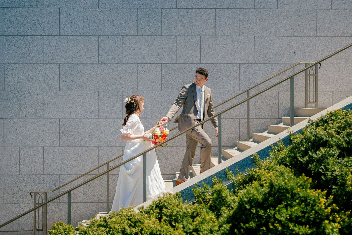 Couple exchanging items on modern architectural staircase.