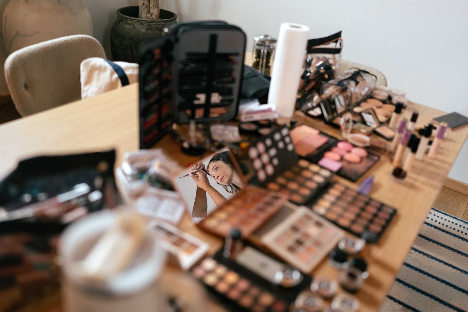 Makeup products and brushes arranged on wooden table for wedding preparation.