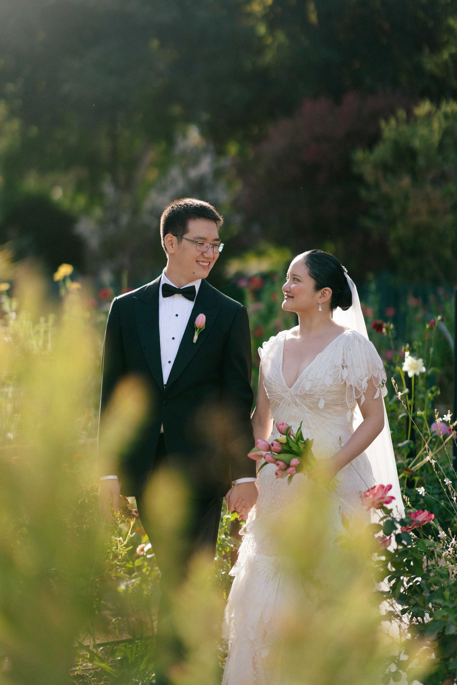 Elegant couple sharing a tender moment in a blooming garden with soft natural lighting.
