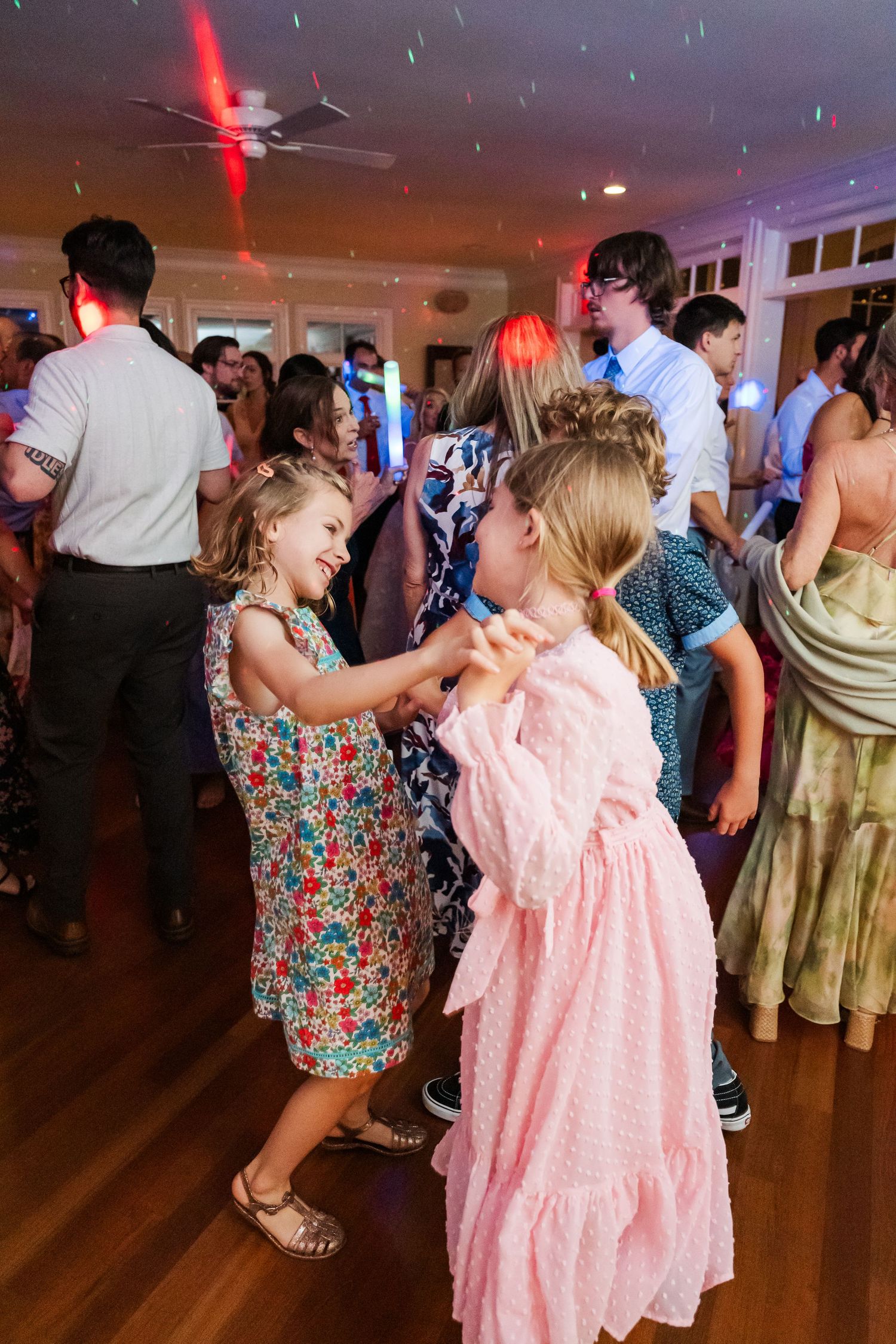 Young guests in colorful dresses dancing at a lively wedding reception.