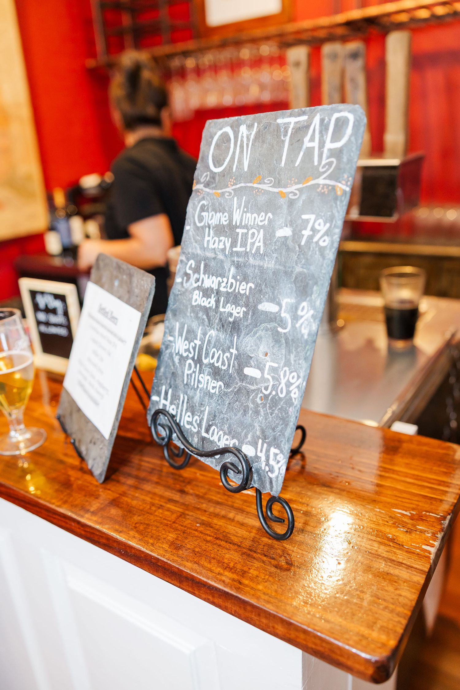 Rustic wooden bar with chalkboard drink menu signs displayed on a counter.