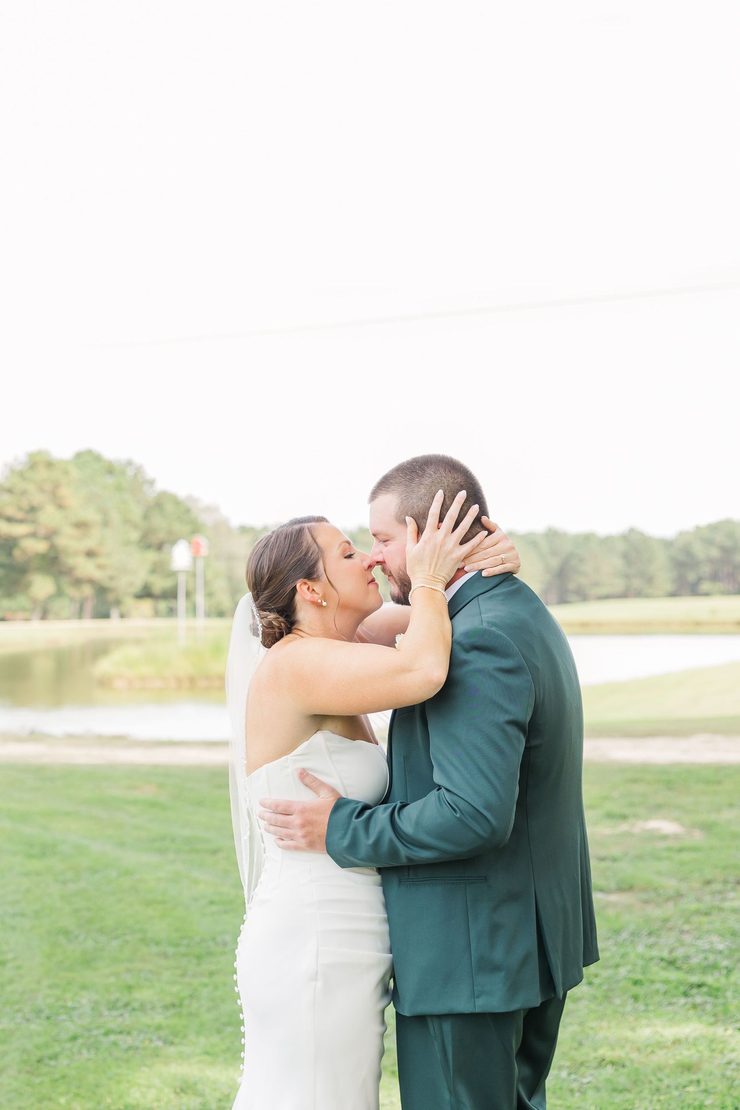 A couple shares a romantic first kiss moment outdoors in a grassy field.