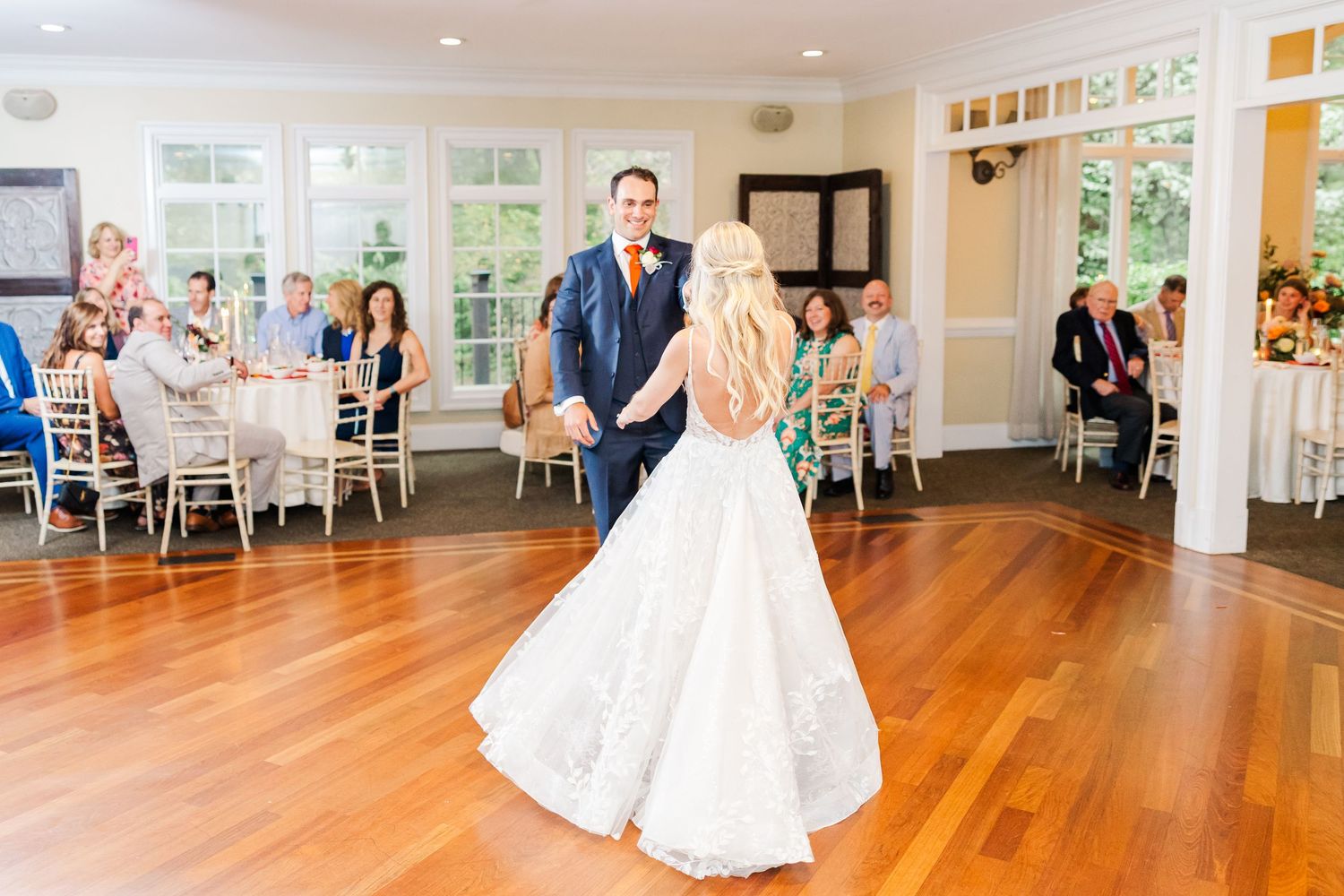 Wedding reception venue with hardwood floors, white columns and large windows letting in natural light.