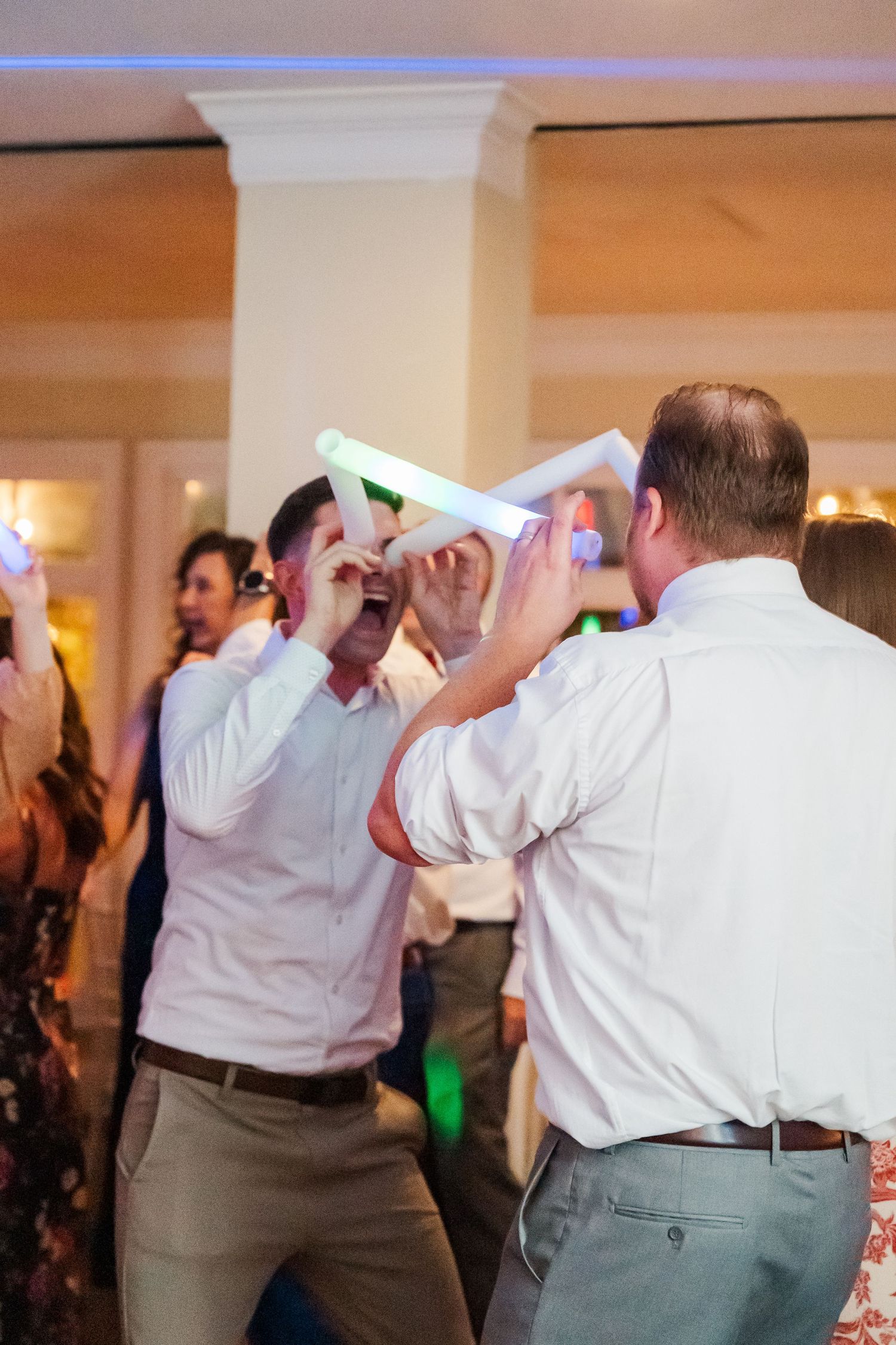 Wedding guests dancing with napkins in the air during reception celebration.