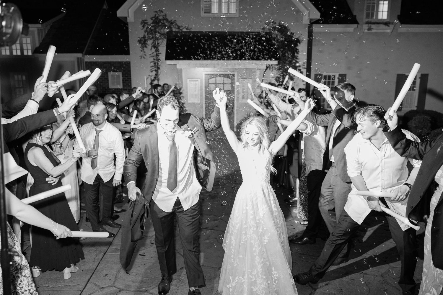 Wedding guests jump and dance in celebration during an outdoor evening reception.