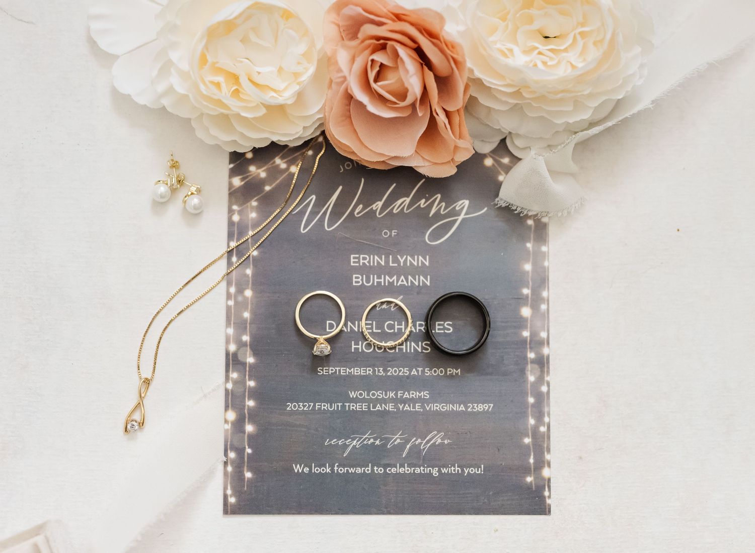 Elegant wedding invitation suite with peach and cream roses, gray acrylic cards, and gold ring details on white marble surface.