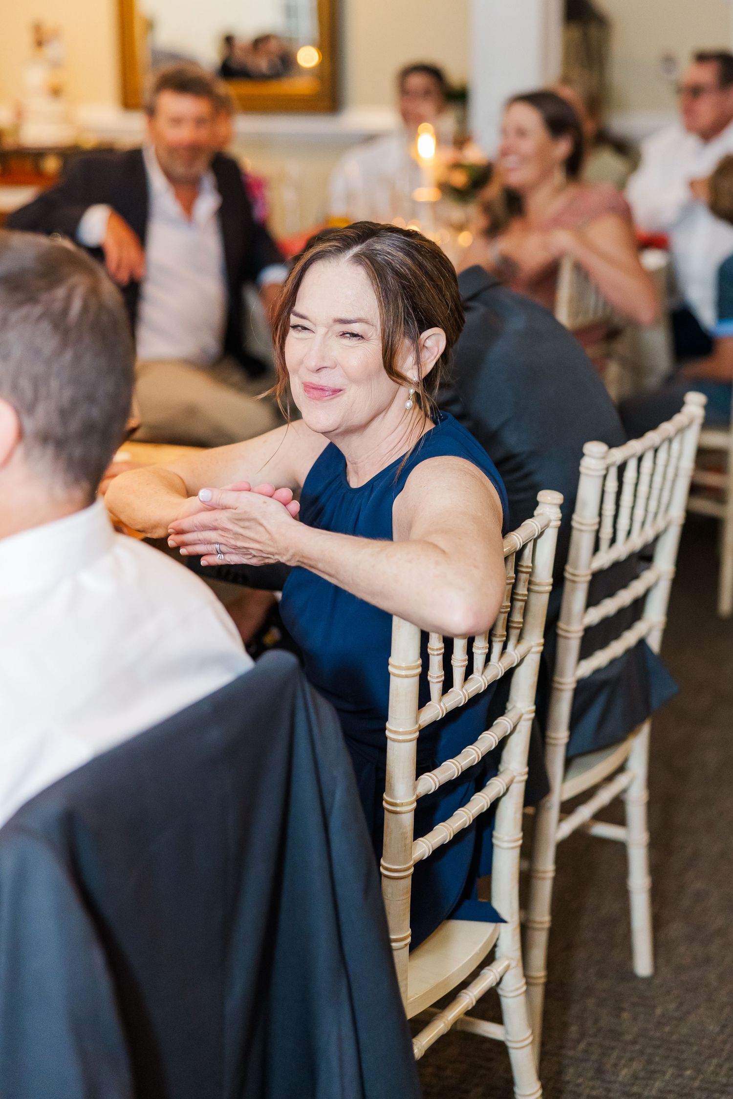 Wedding guests seated at reception tables with chiavari chairs in an elegant indoor setting.