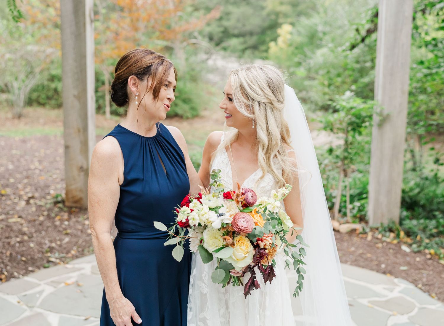 Navy blue bridesmaid dress and white bridal gown photographed in an outdoor garden setting.