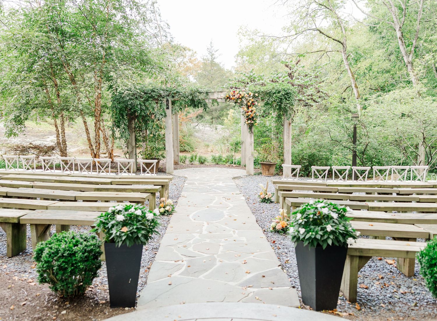 A rustic wooden bench and walkway surrounded by lush greenery in an outdoor garden setting.