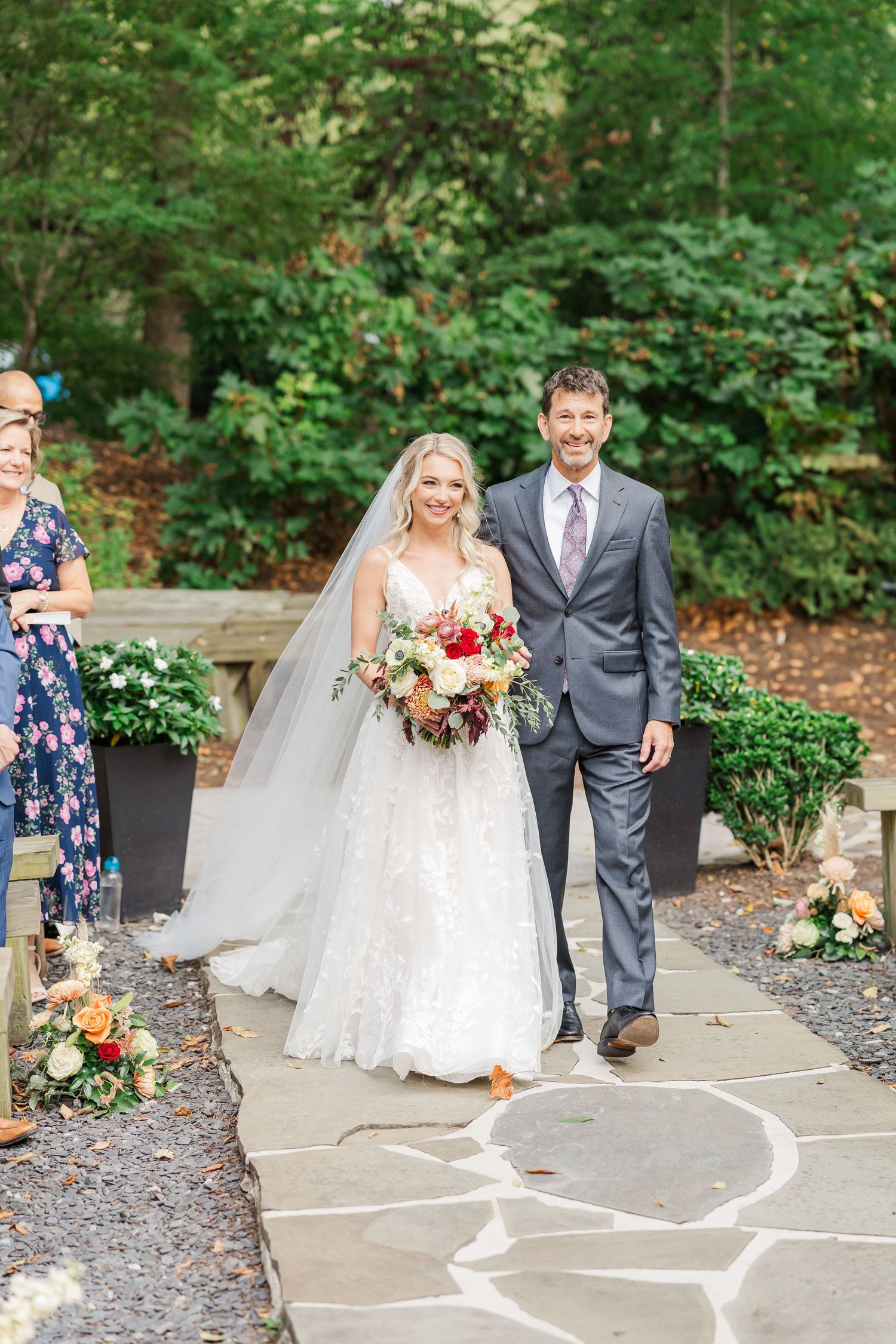 Wedding couple walking along stone path with heart shape drawn in chalk during outdoor garden ceremony.