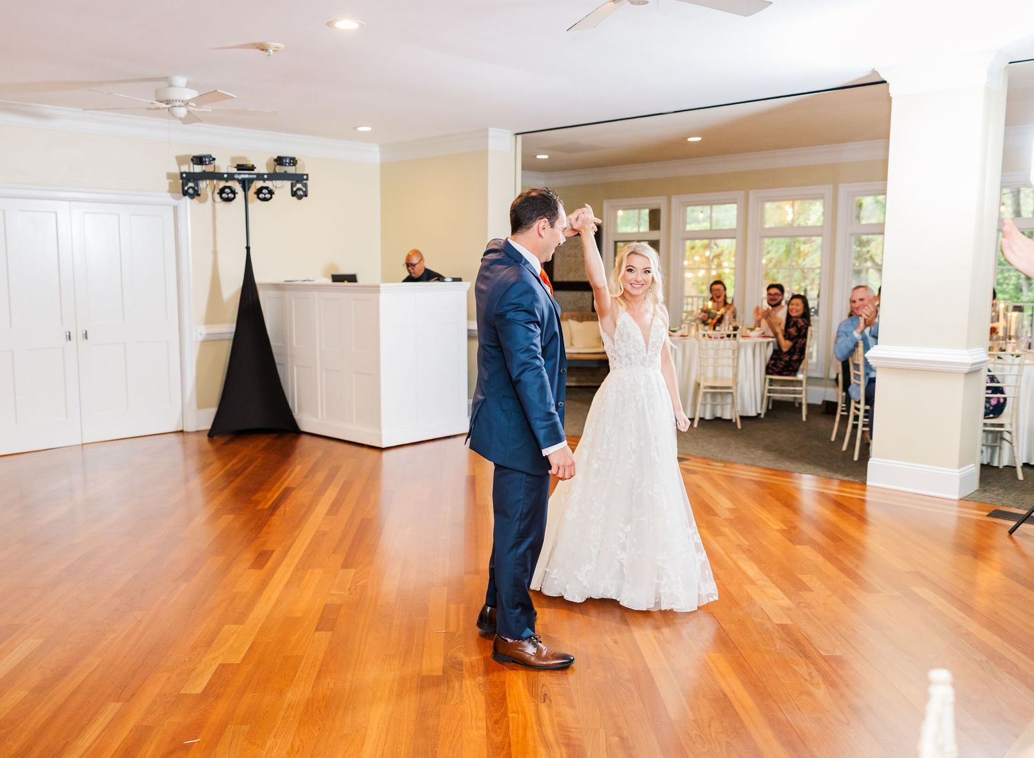 Large empty ballroom with polished hardwood floors and white walls ready for an event.
