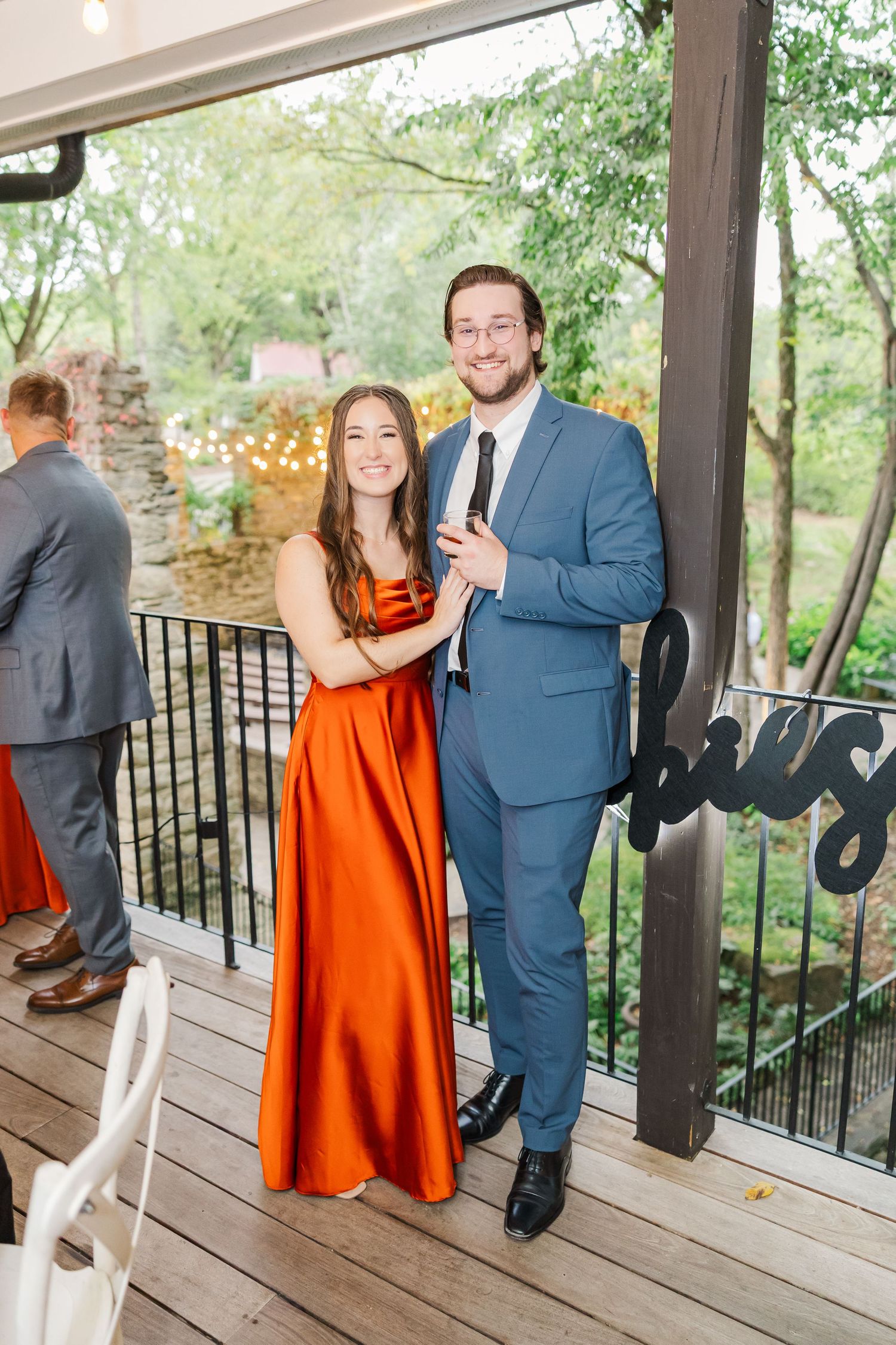 A couple shares a romantic moment on a covered porch decorated with string lights.