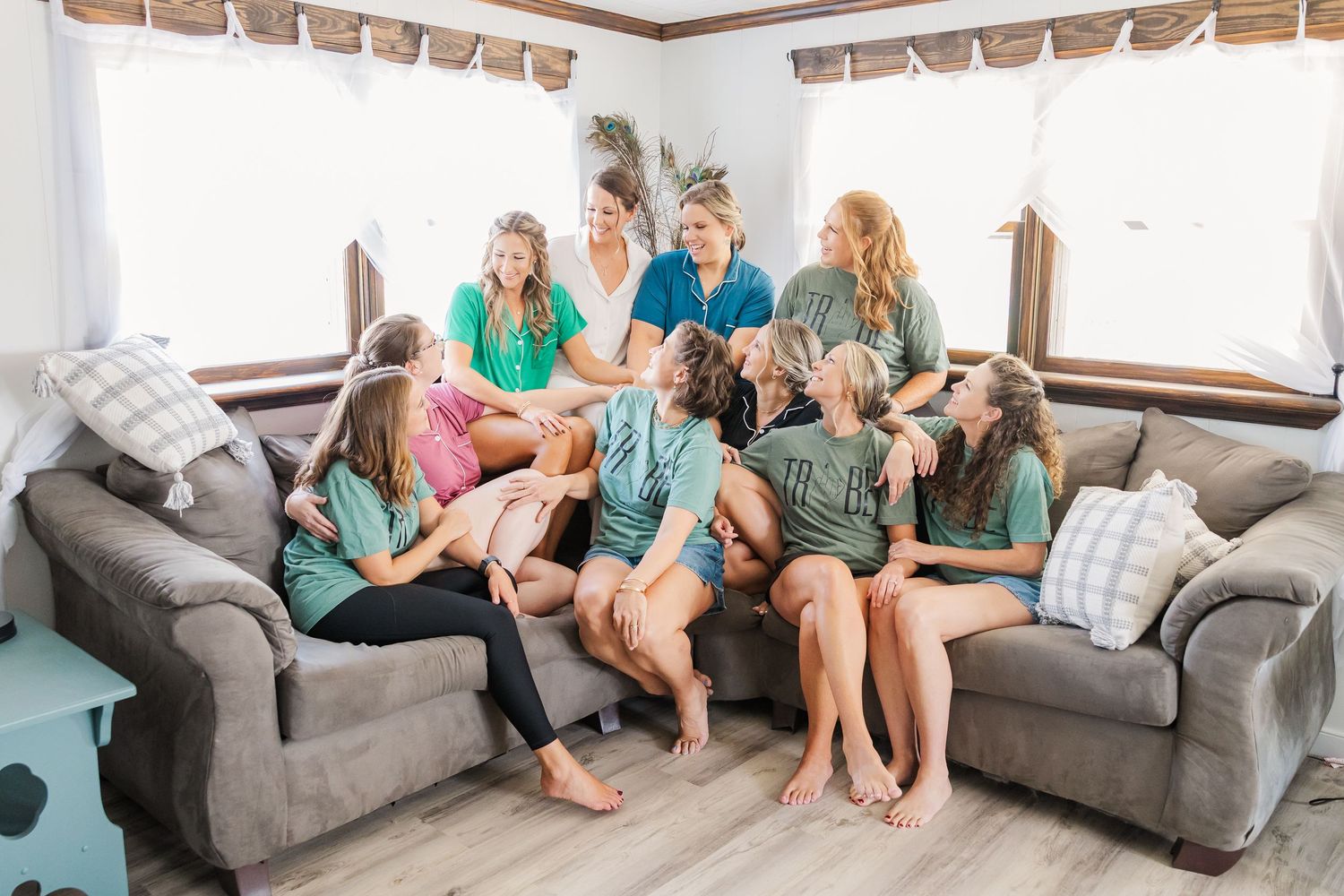 Group sitting on a gray sectional sofa in a bright living room with Roman shades on the windows.