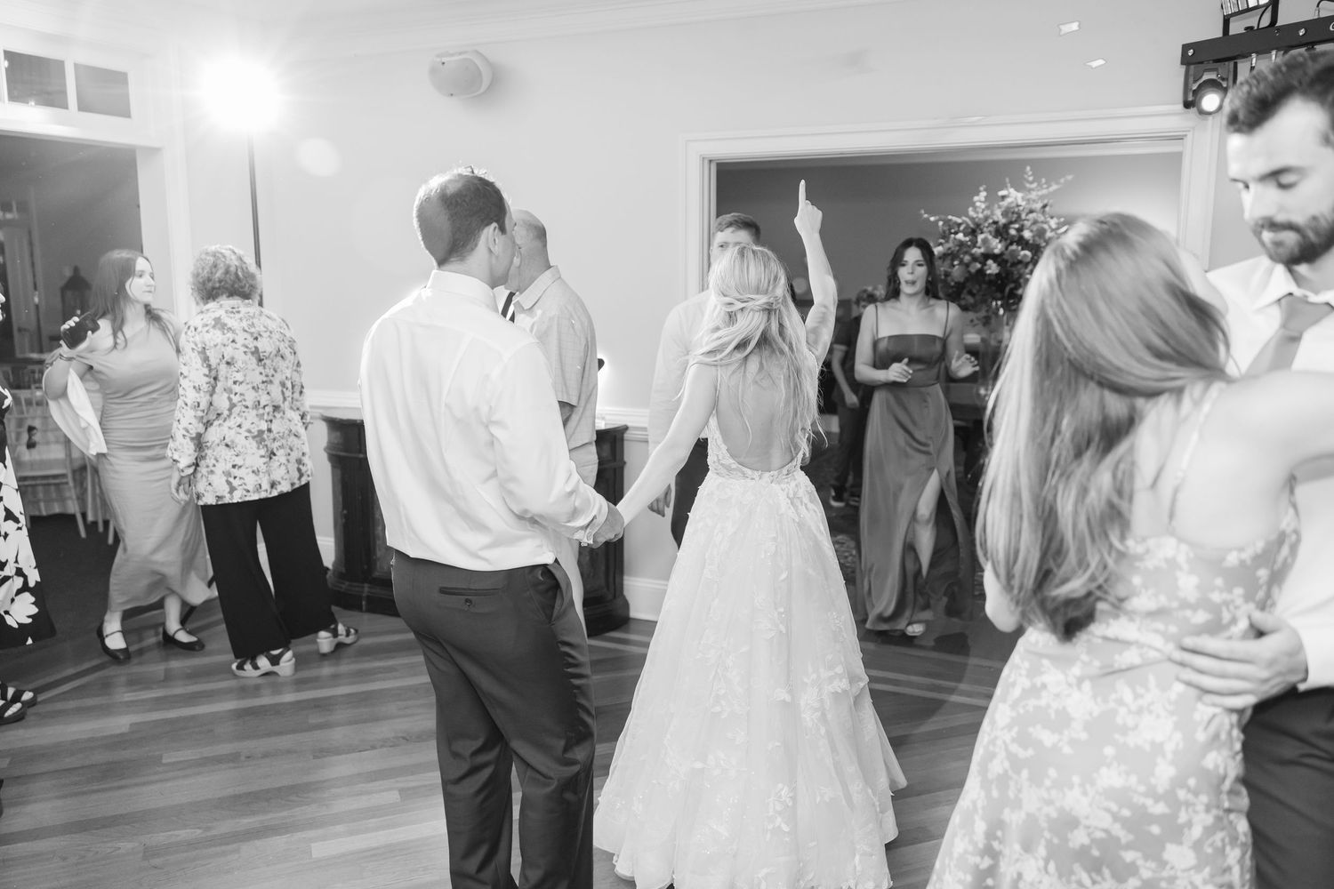 Wedding guests dance and celebrate together on a reception dance floor during an evening celebration.