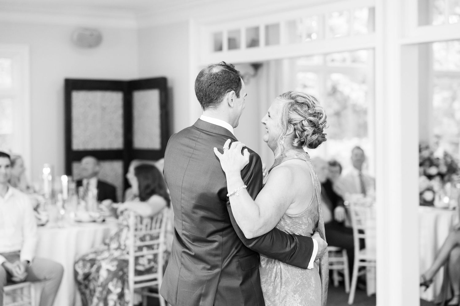 Wedding reception dance floor filled with guests celebrating under white ceiling decor.