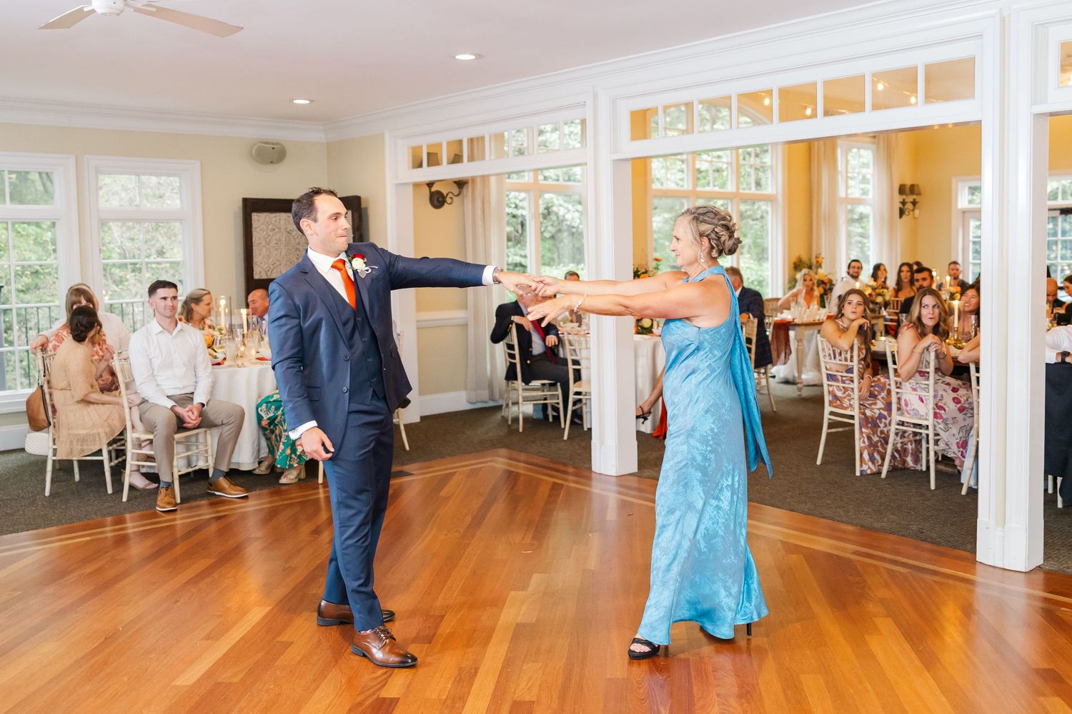 Panoramic view of wedding reception dance floor with hardwood flooring and white pillars.