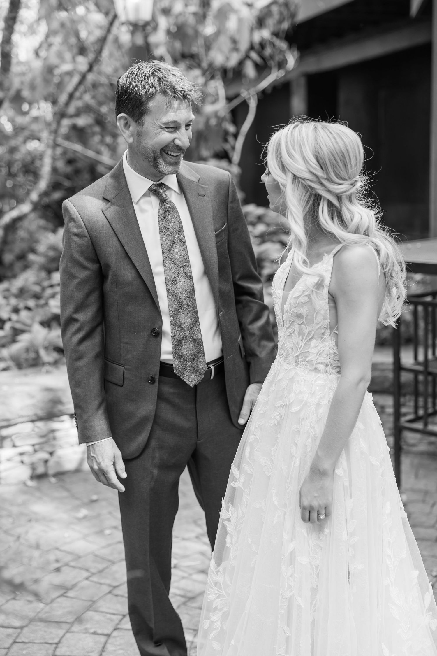 Black and white wedding photos showing candid moments between a bride in a lace dress and groom in a suit.