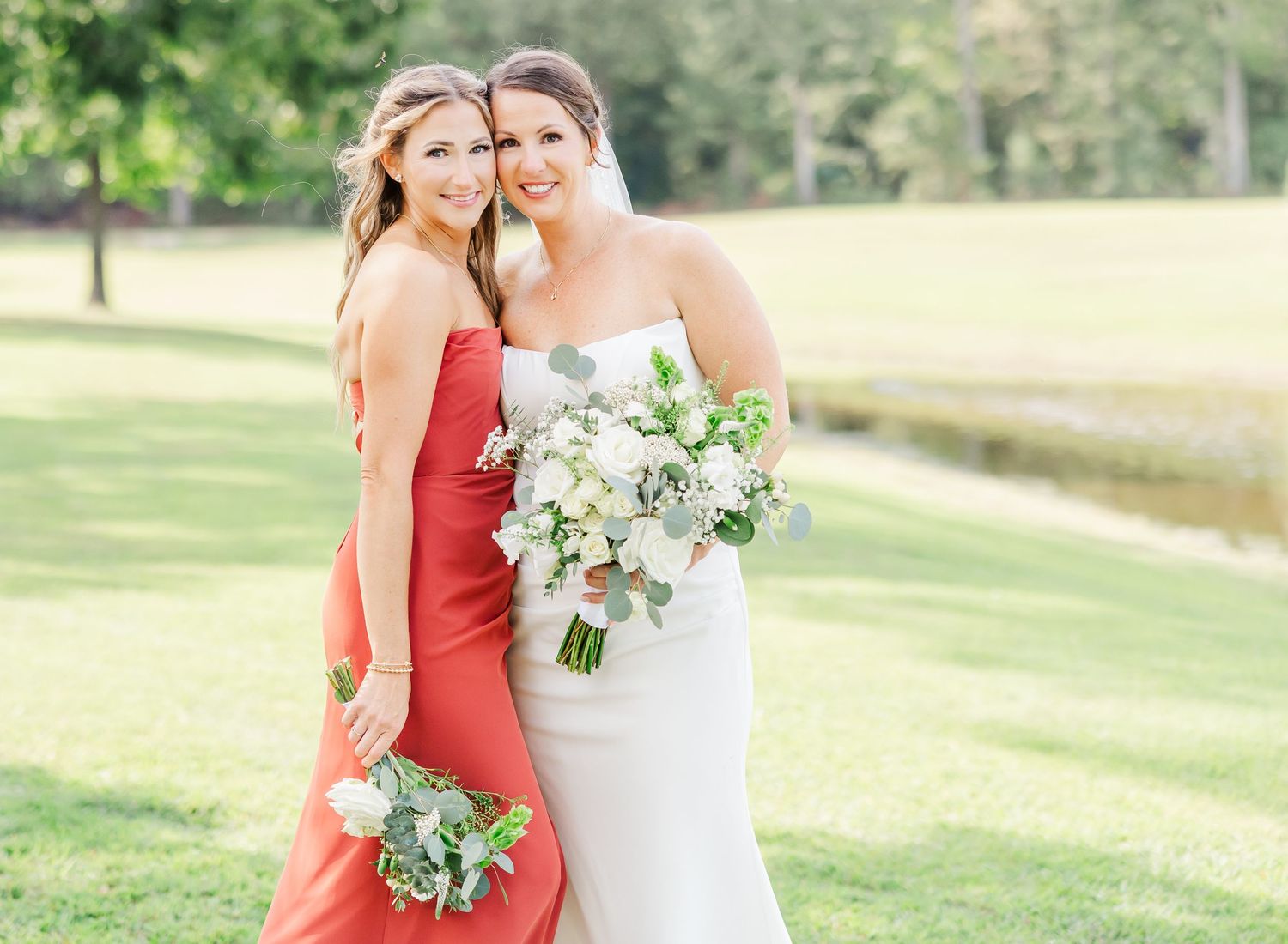 Bridesmaids in jewel-toned dresses pose with bouquets outdoors on sunny day.