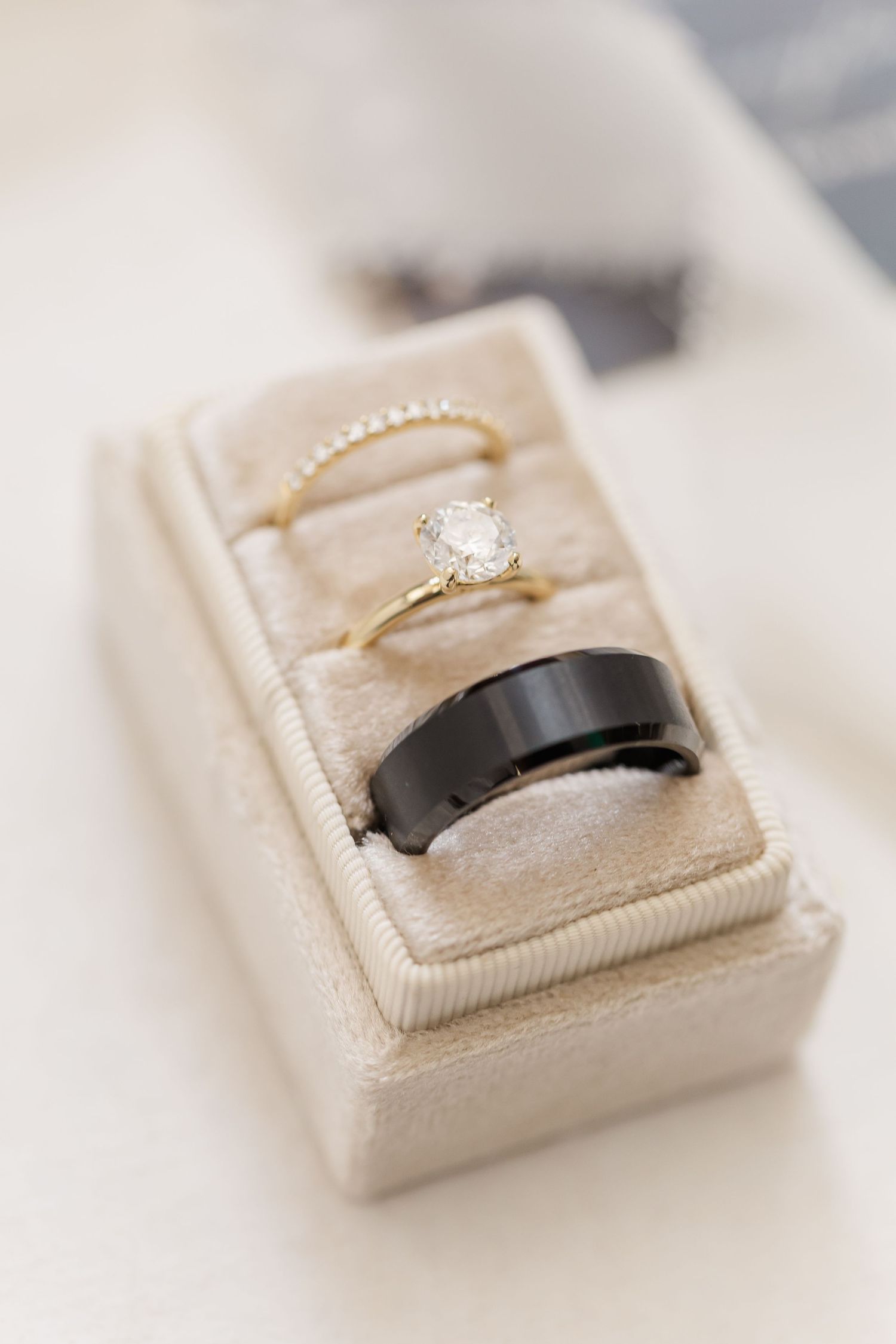Three elegant engagement rings with diamonds displayed in cream-colored velvet ring boxes from different angles.
