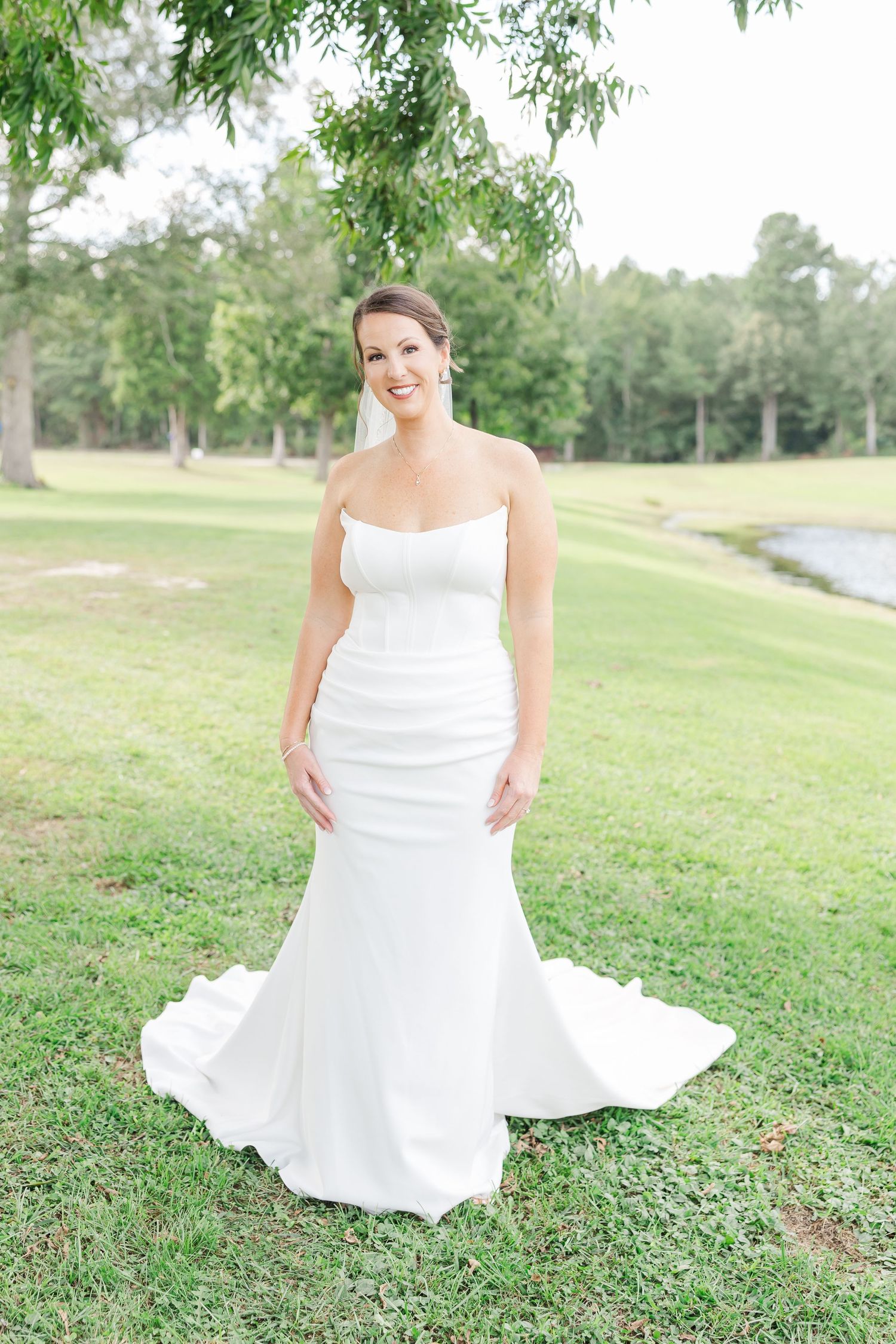 White wedding dress flowing across green grass in an outdoor garden setting.