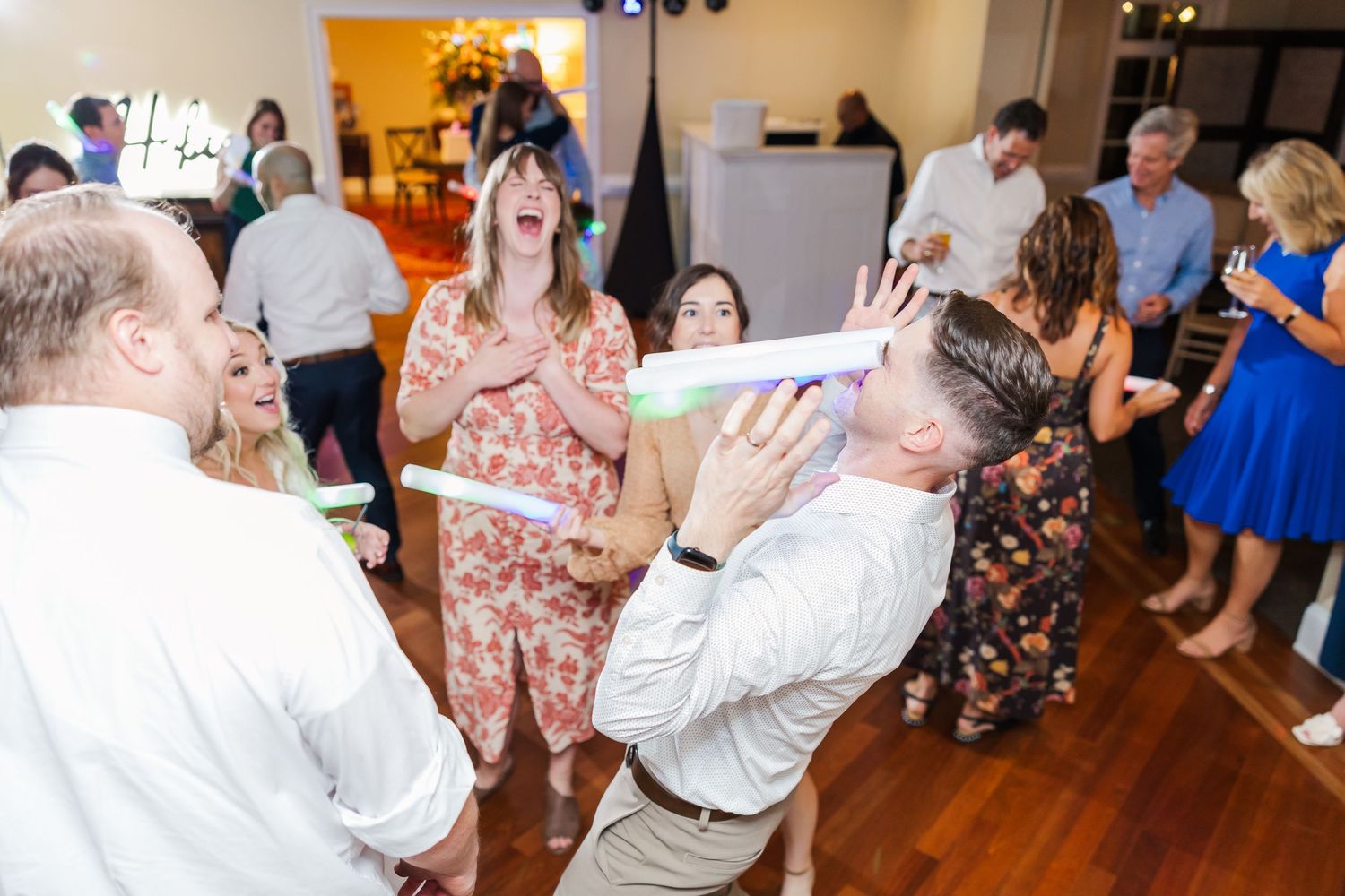 Wedding reception dance party with guests celebrating on a polished wooden floor.