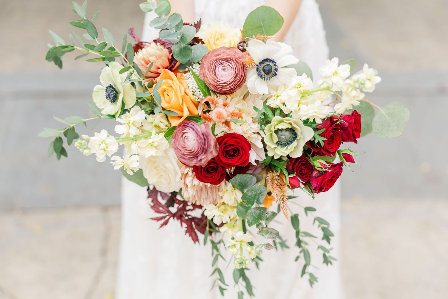 Delicate floral arrangements with blush pink and burgundy roses mixed with white blooms and greenery in elegant vases.