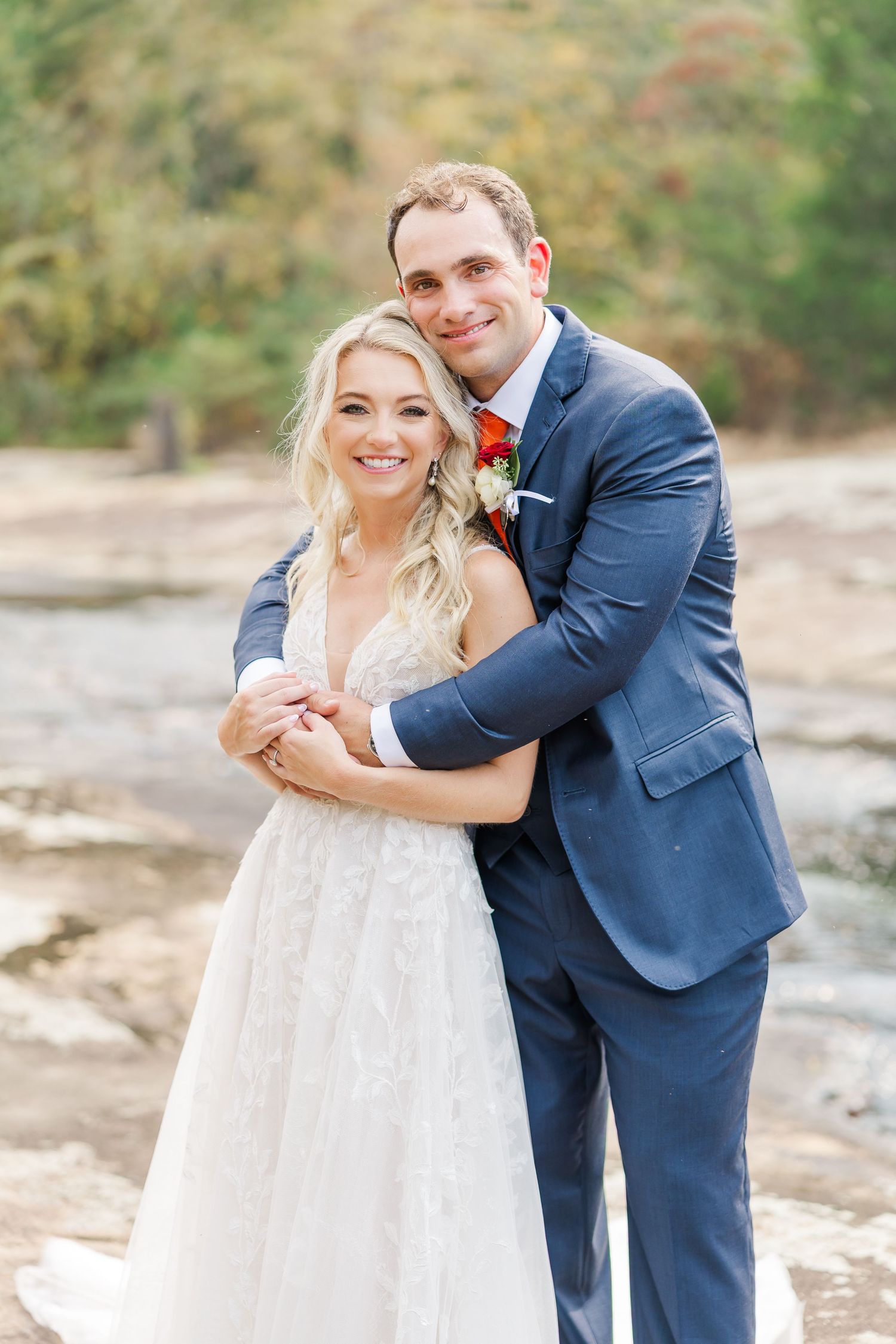 A romantic wedding portrait of a couple in navy and white against an autumn backdrop.