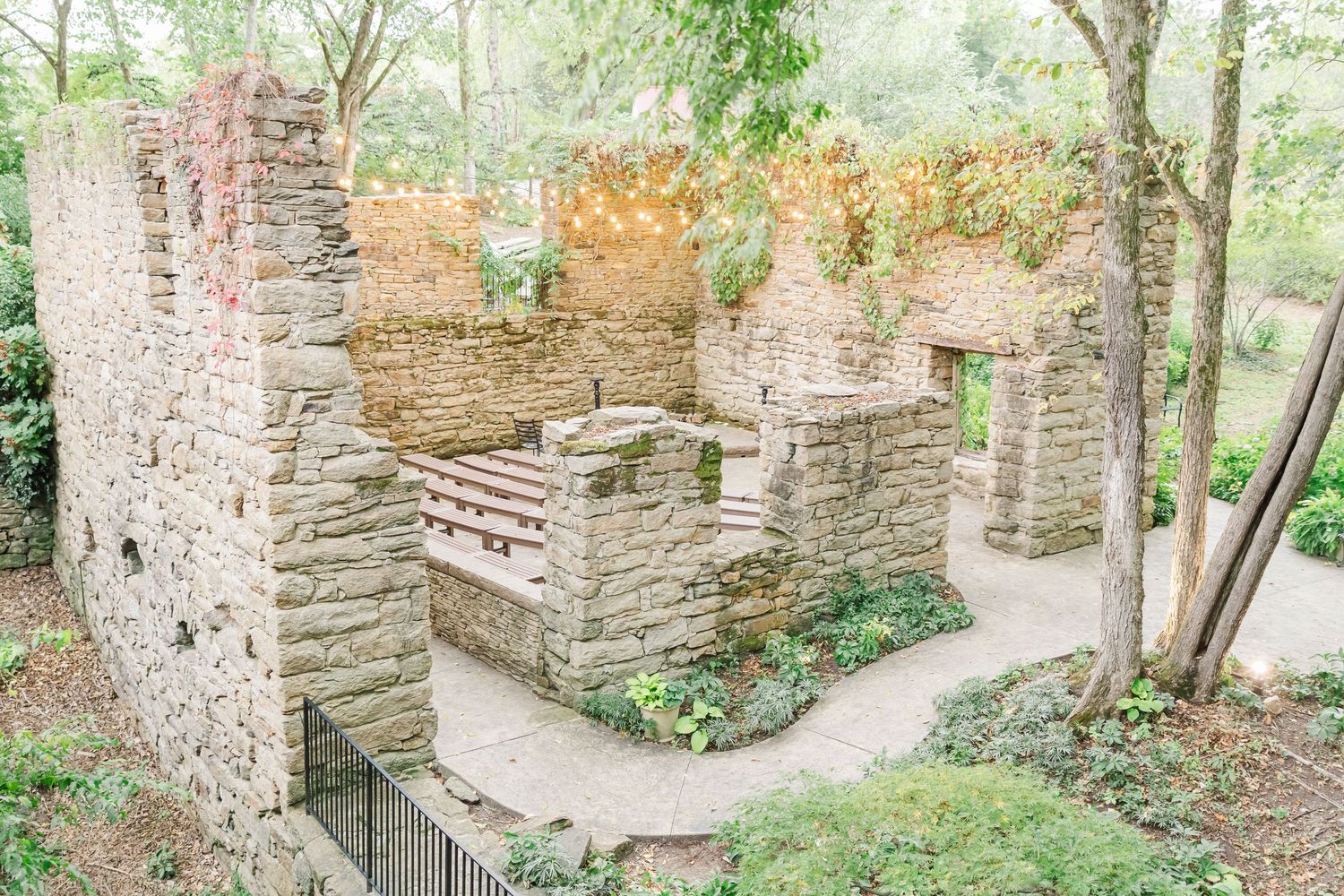 Historic stone ruins and pathways surrounded by lush green trees and vegetation.