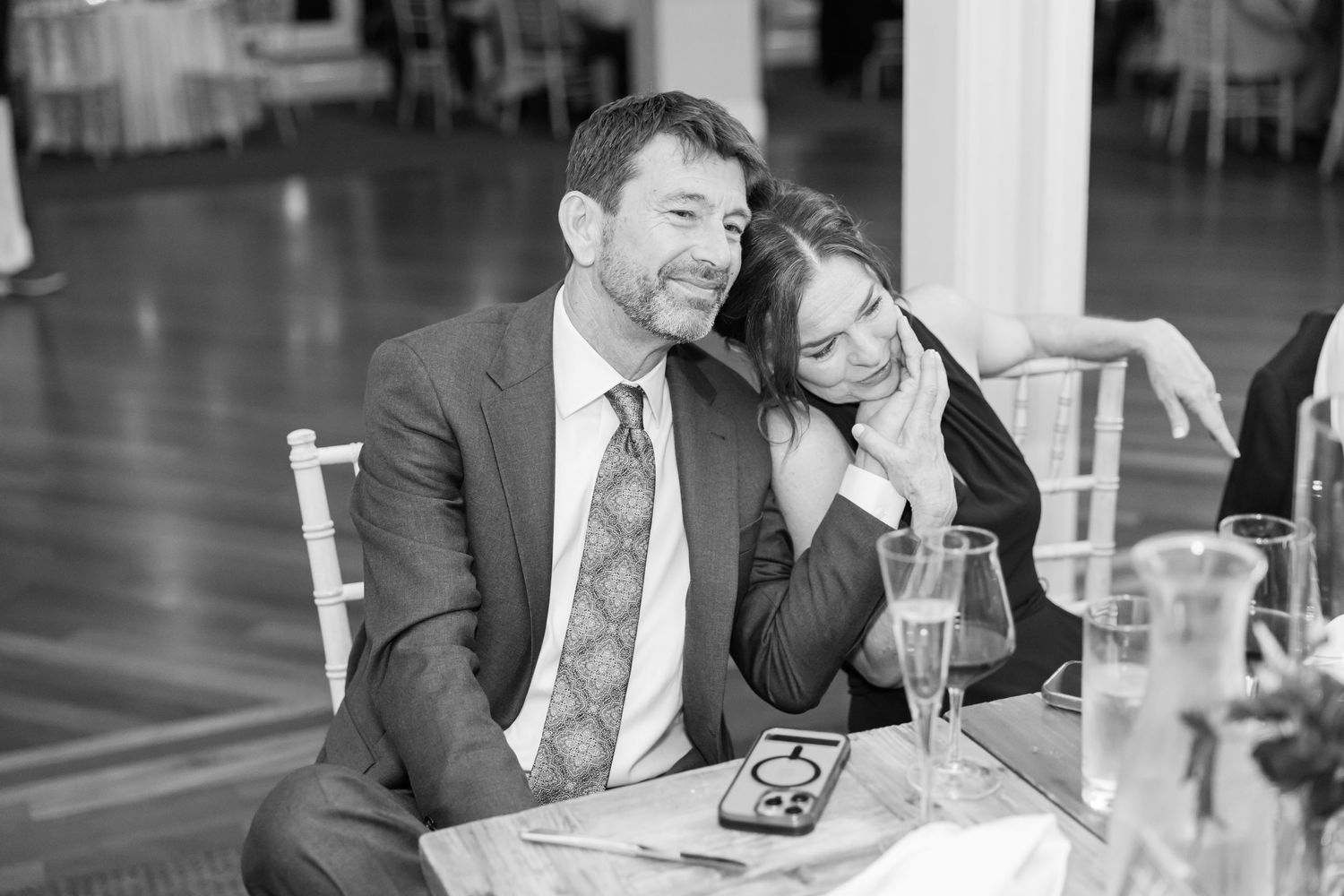 Wedding reception guests enjoying conversation and drinks at elegantly set tables.