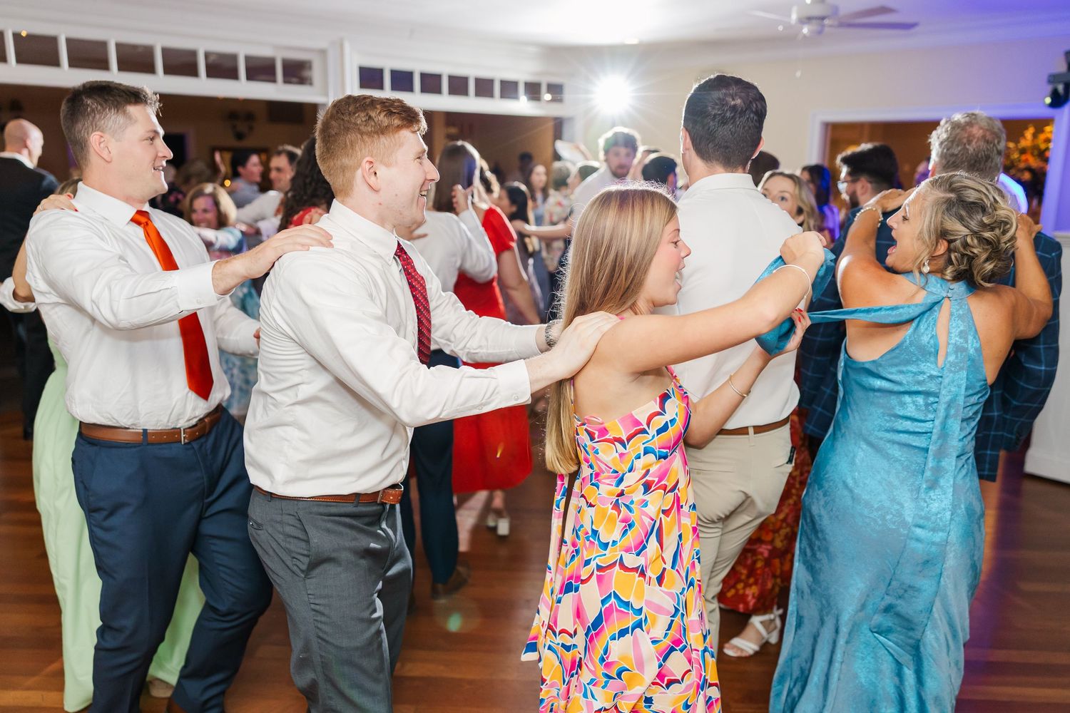 Couples dancing together at a wedding reception with colorful lighting.