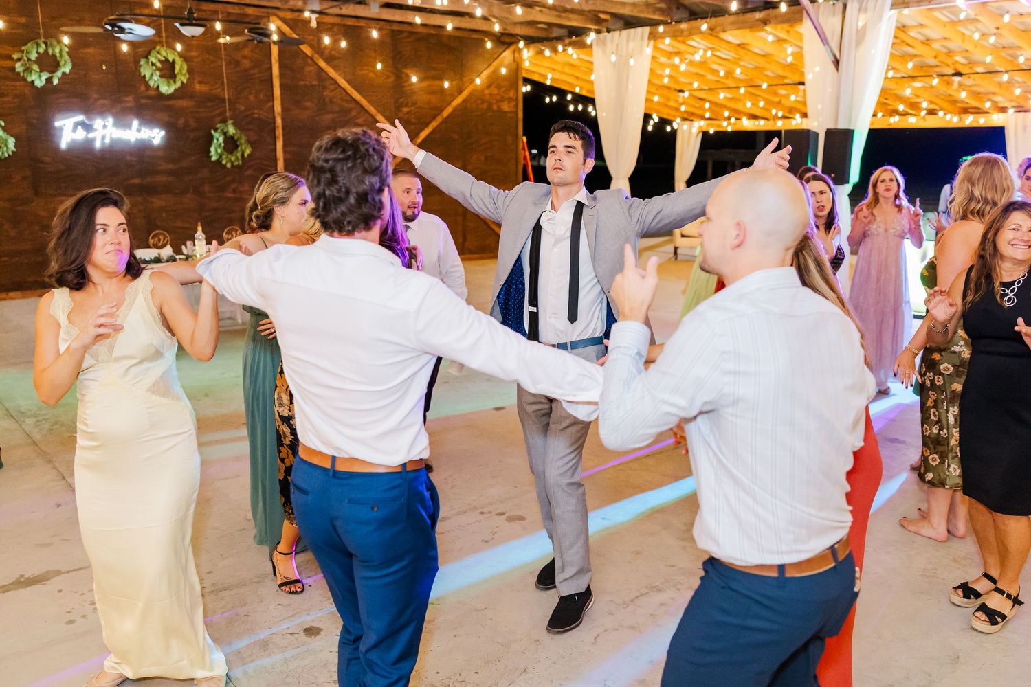 Guests celebrate on the dance floor at The Houchins wedding reception under festive string lights.