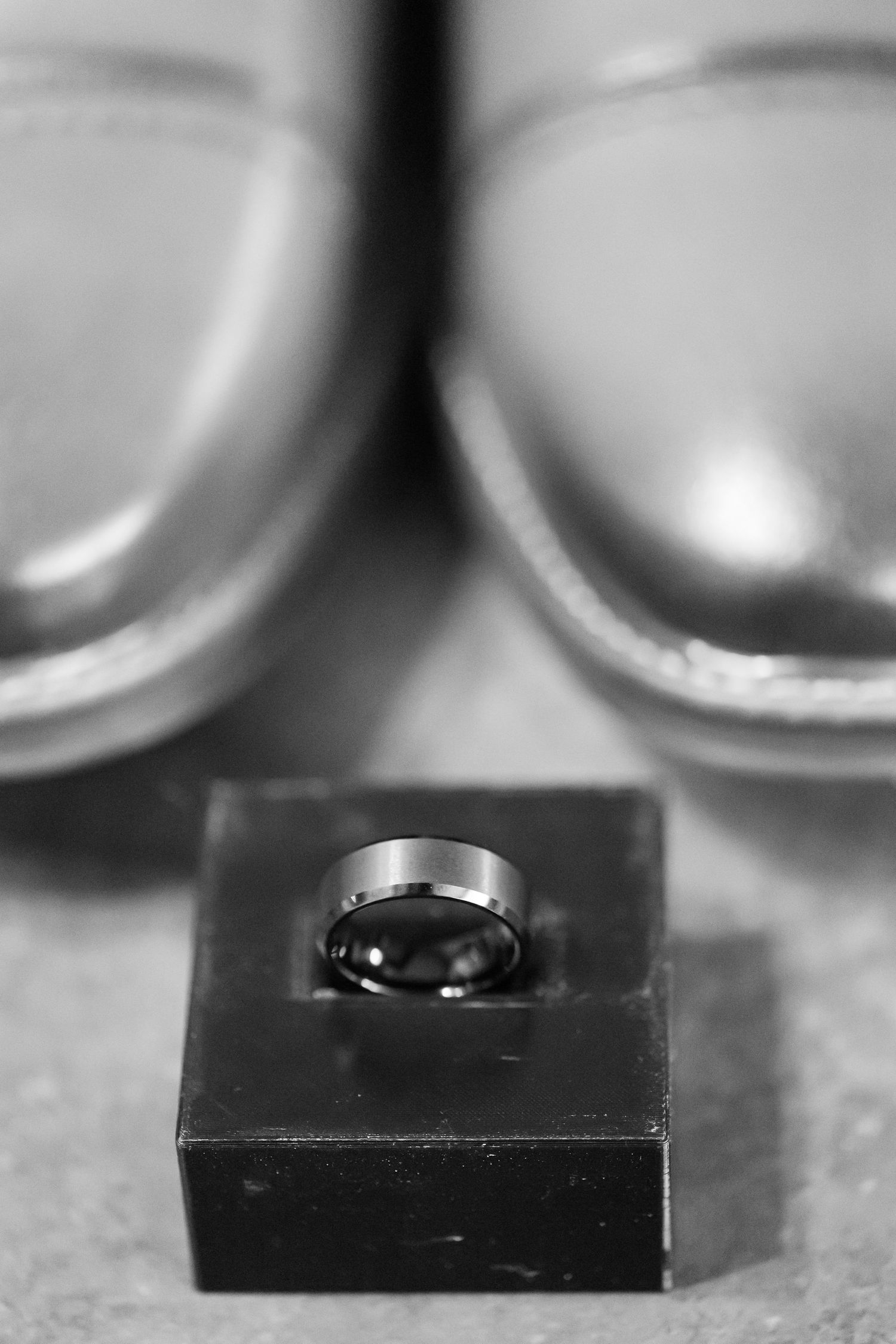 Close-up macro shot of wedding rings on a black surface with blurred bokeh background.