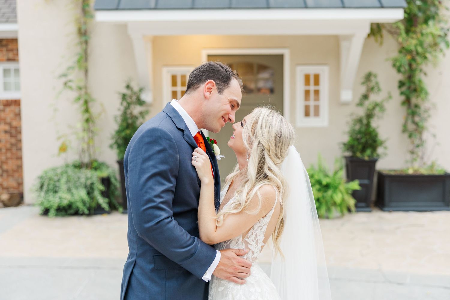 A romantic couple shares a tender moment in an elegant courtyard garden setting during their wedding celebration.