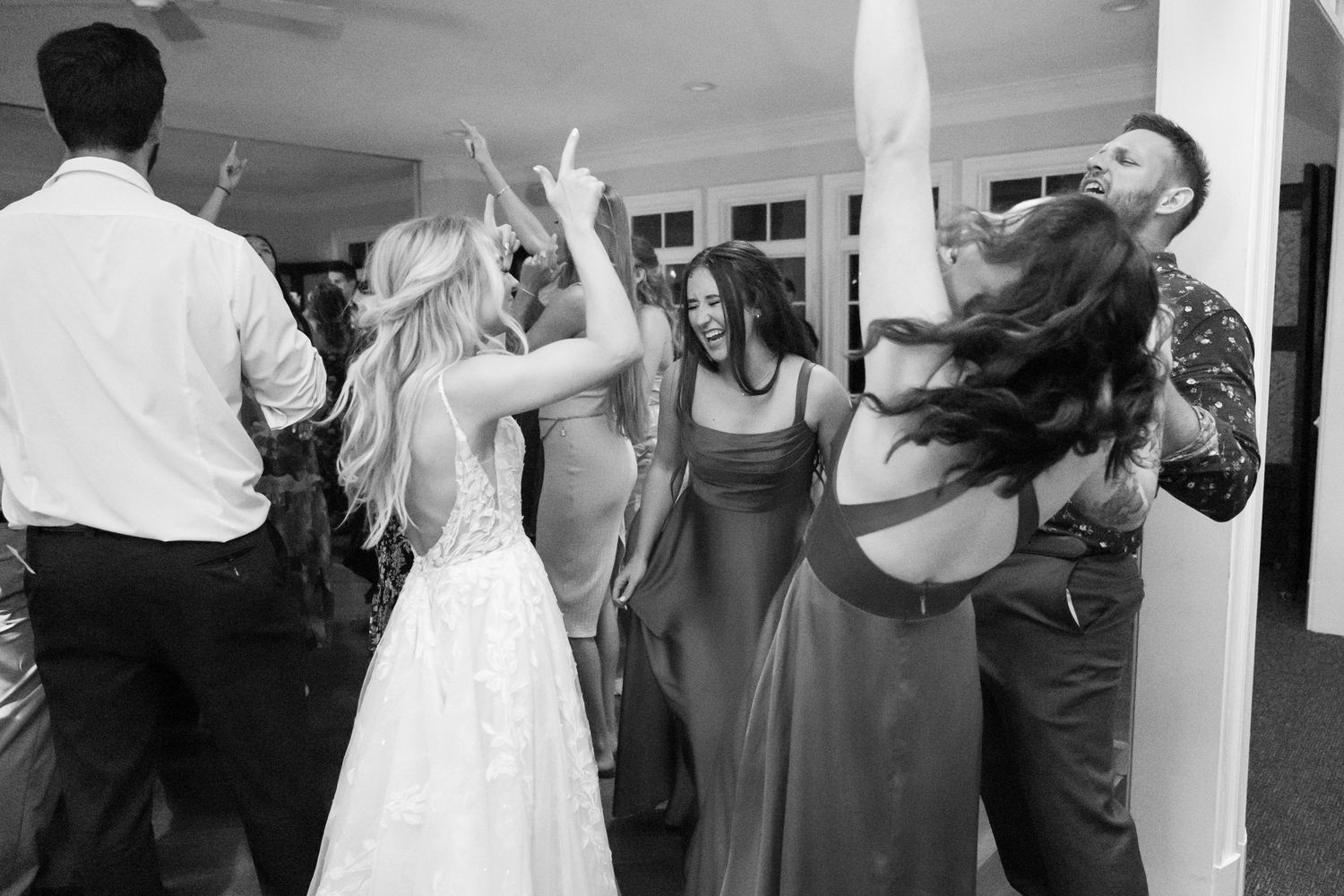 Black and white photo of wedding guests dancing and celebrating on the dance floor.