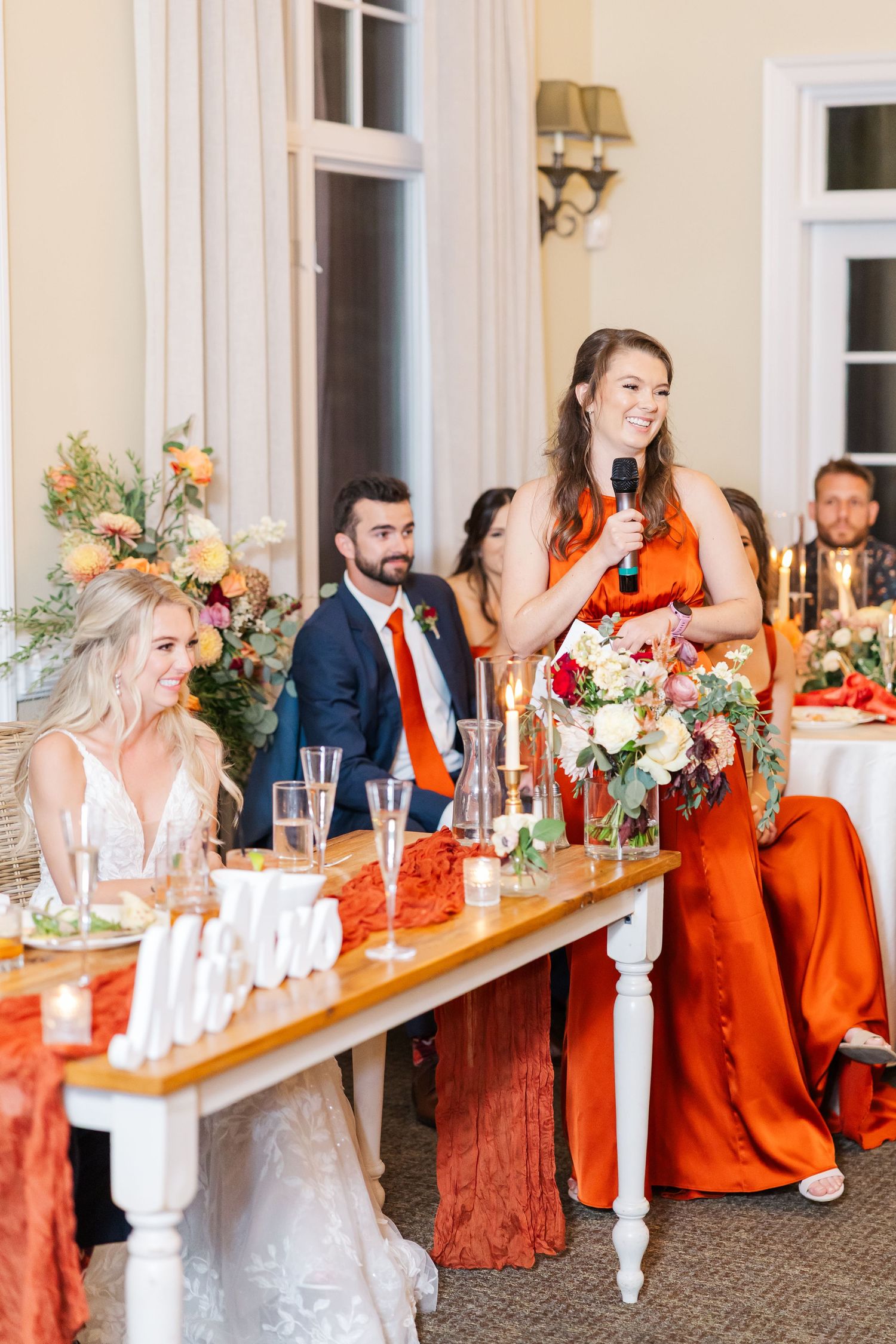 Wedding reception celebration with orange and white decor at an elegant indoor venue.
