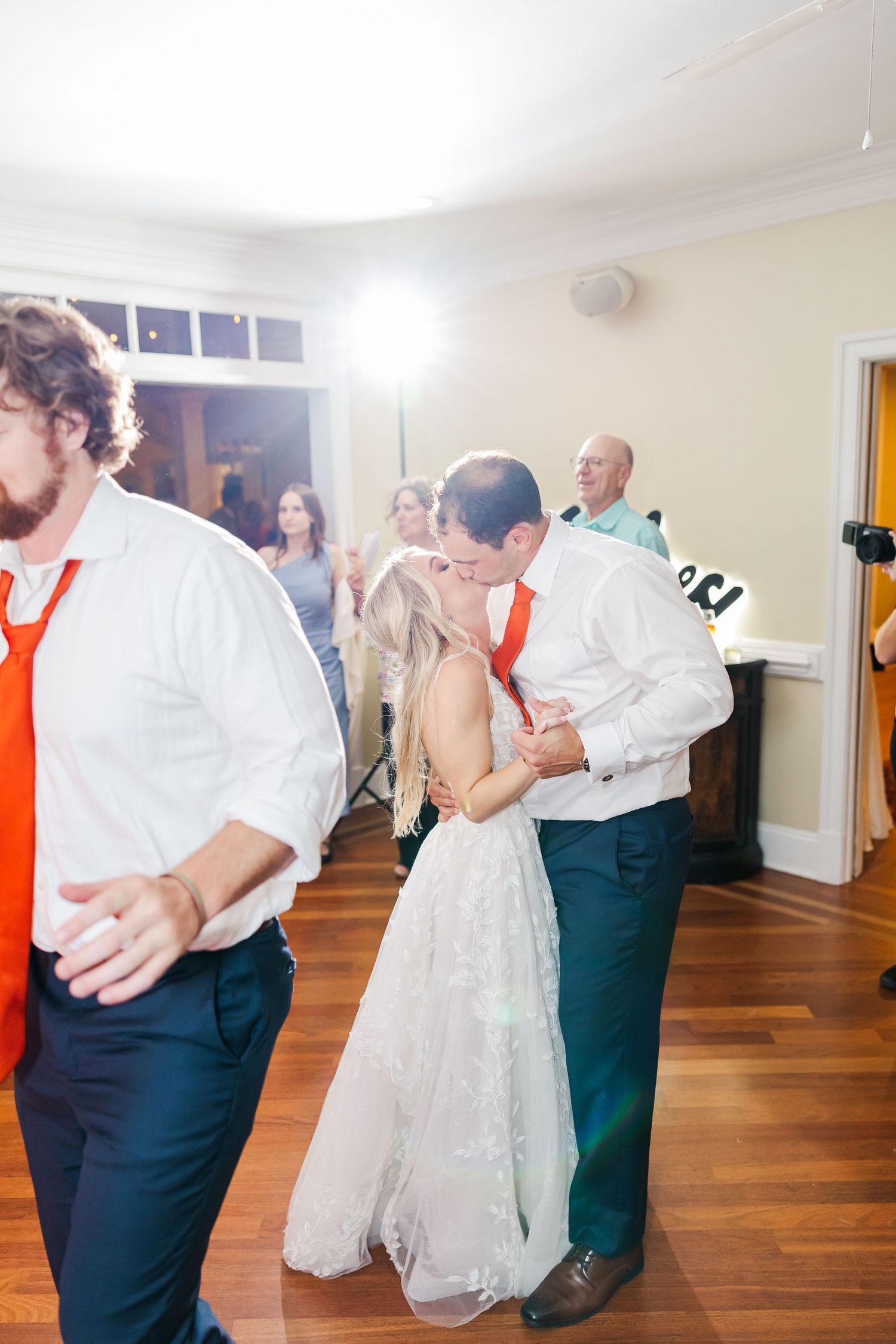 Couples twirling and dancing on a hardwood floor at an elegant wedding reception.