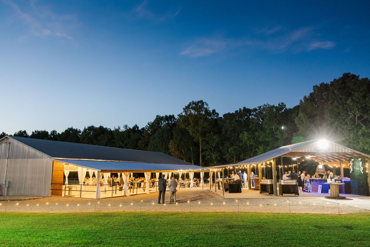 Elegant outdoor wedding reception venue illuminated at night with string lights under a clear blue sky.