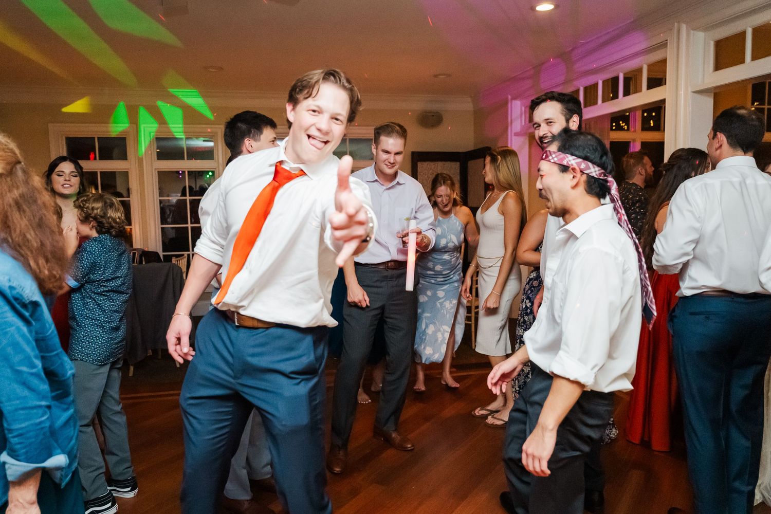 Wedding guests dancing under colored lights at an energetic reception party.