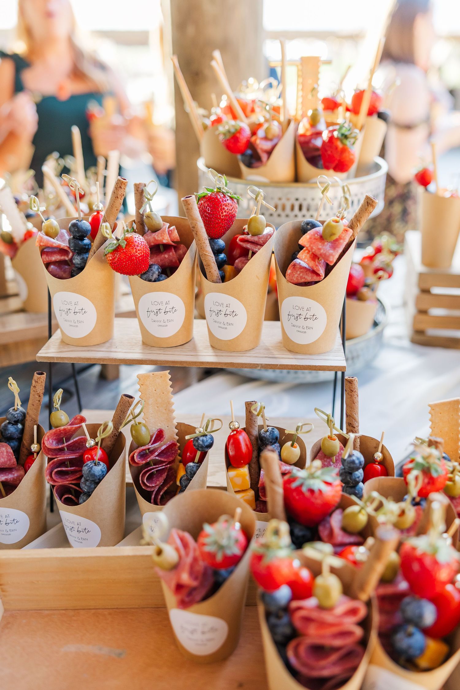 Elegant charcuterie cones filled with strawberries, blueberries, olives, and cured meats displayed on a wooden tiered stand.