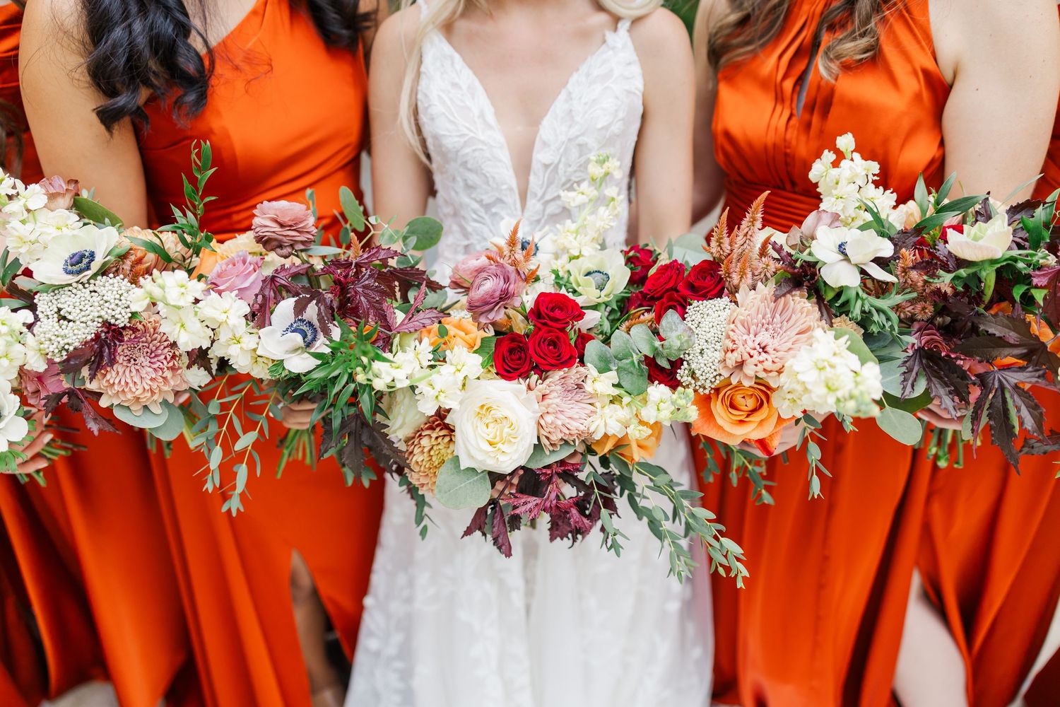 Vibrant orange bridesmaid dresses and colorful floral bouquets create a stunning autumn wedding color palette.