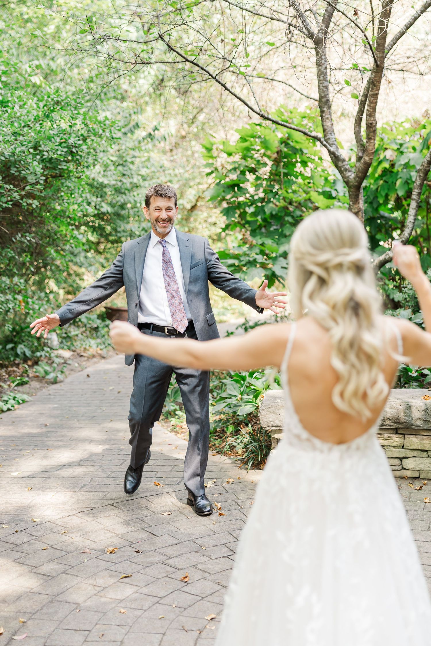 A playful wedding moment on a garden path with the couple dancing and twirling in formal attire.