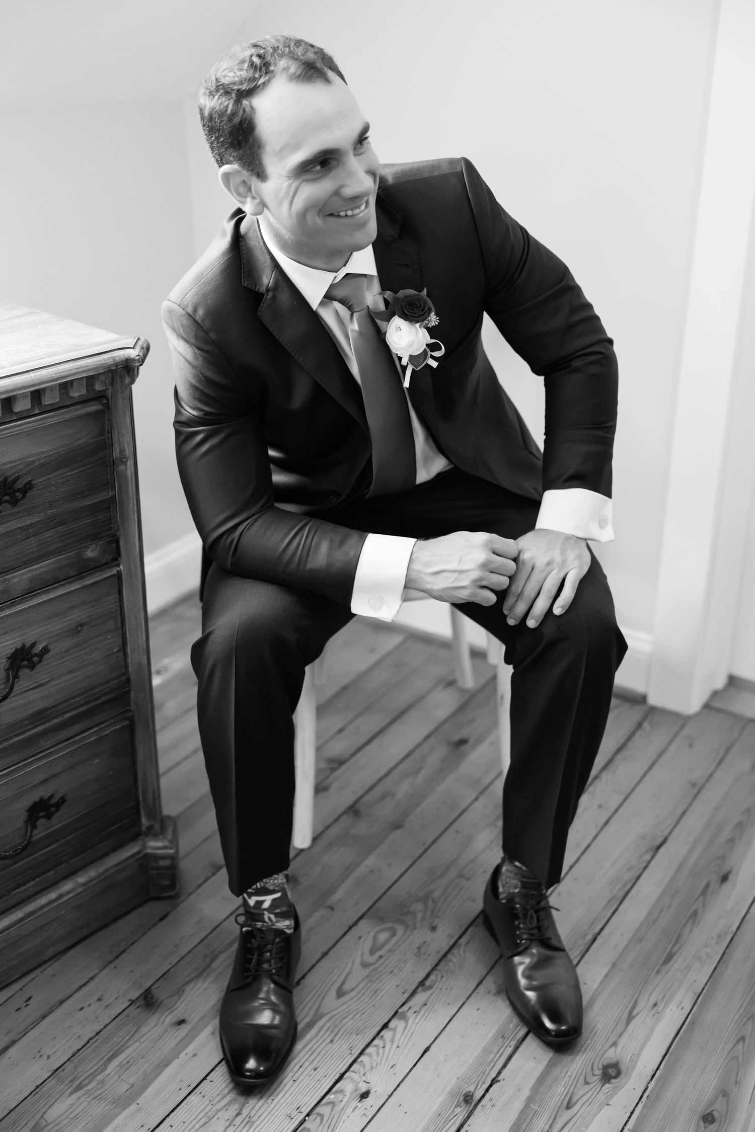 A sequence of black and white photos showing someone in a formal suit sitting on wooden flooring.