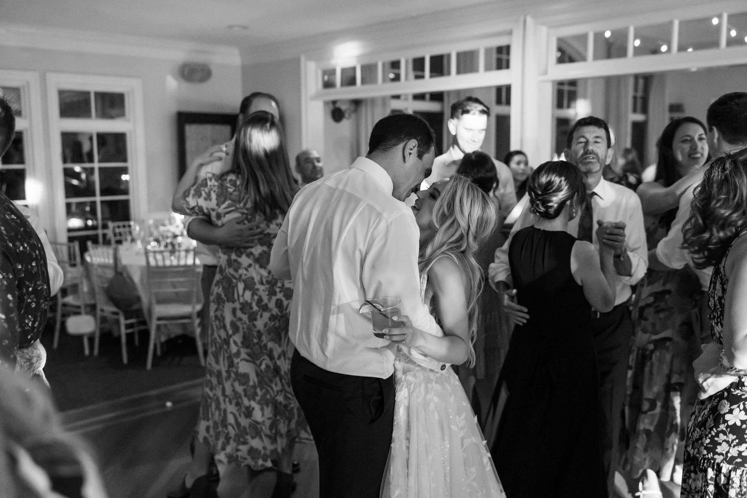Black and white photo of wedding guests dancing and celebrating at reception.